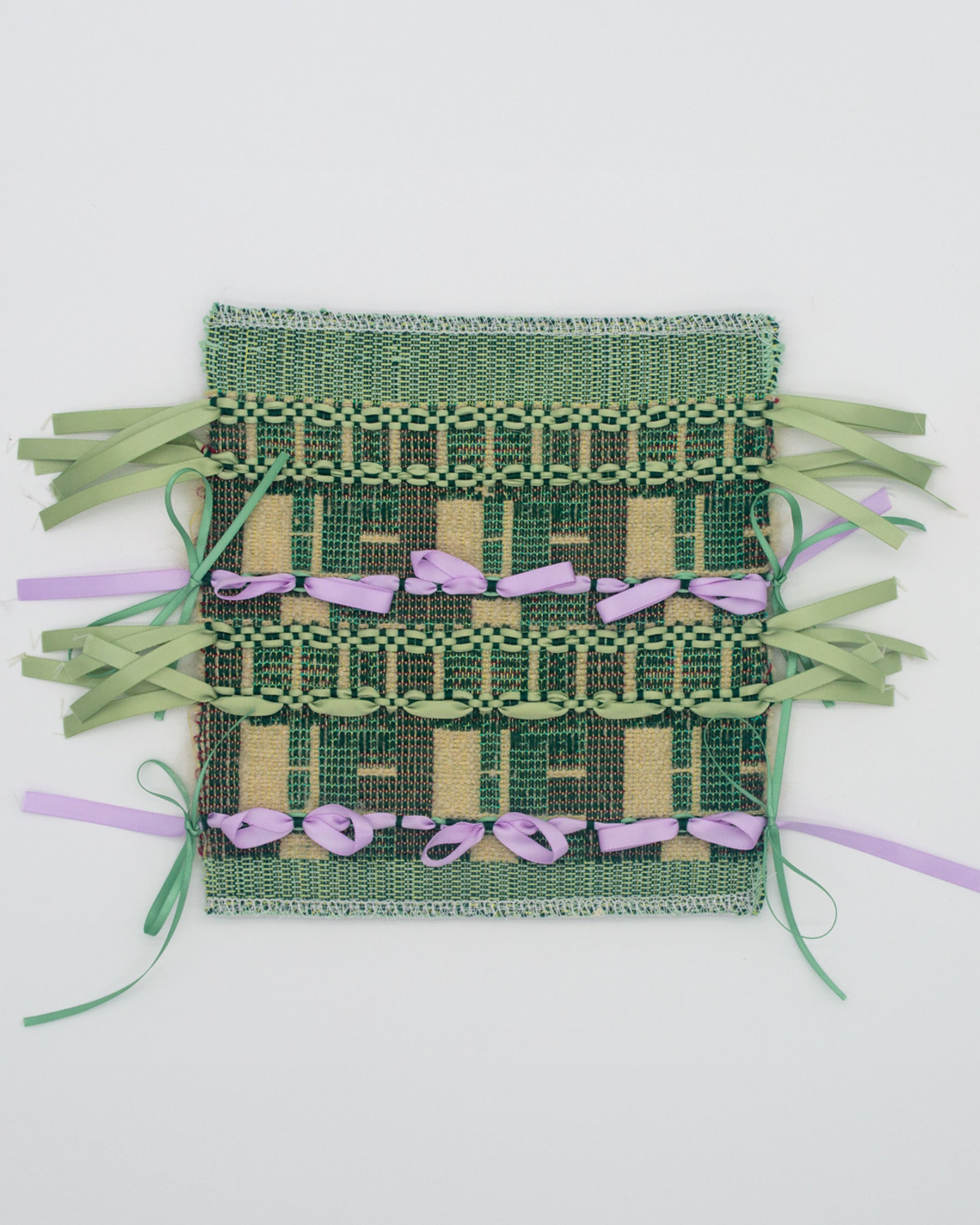 A woven fabric structured by a fragmented grid referencing the Halston House. Sage green and lilac ribbons are tied across the surface in bows, evoking architectural ornament