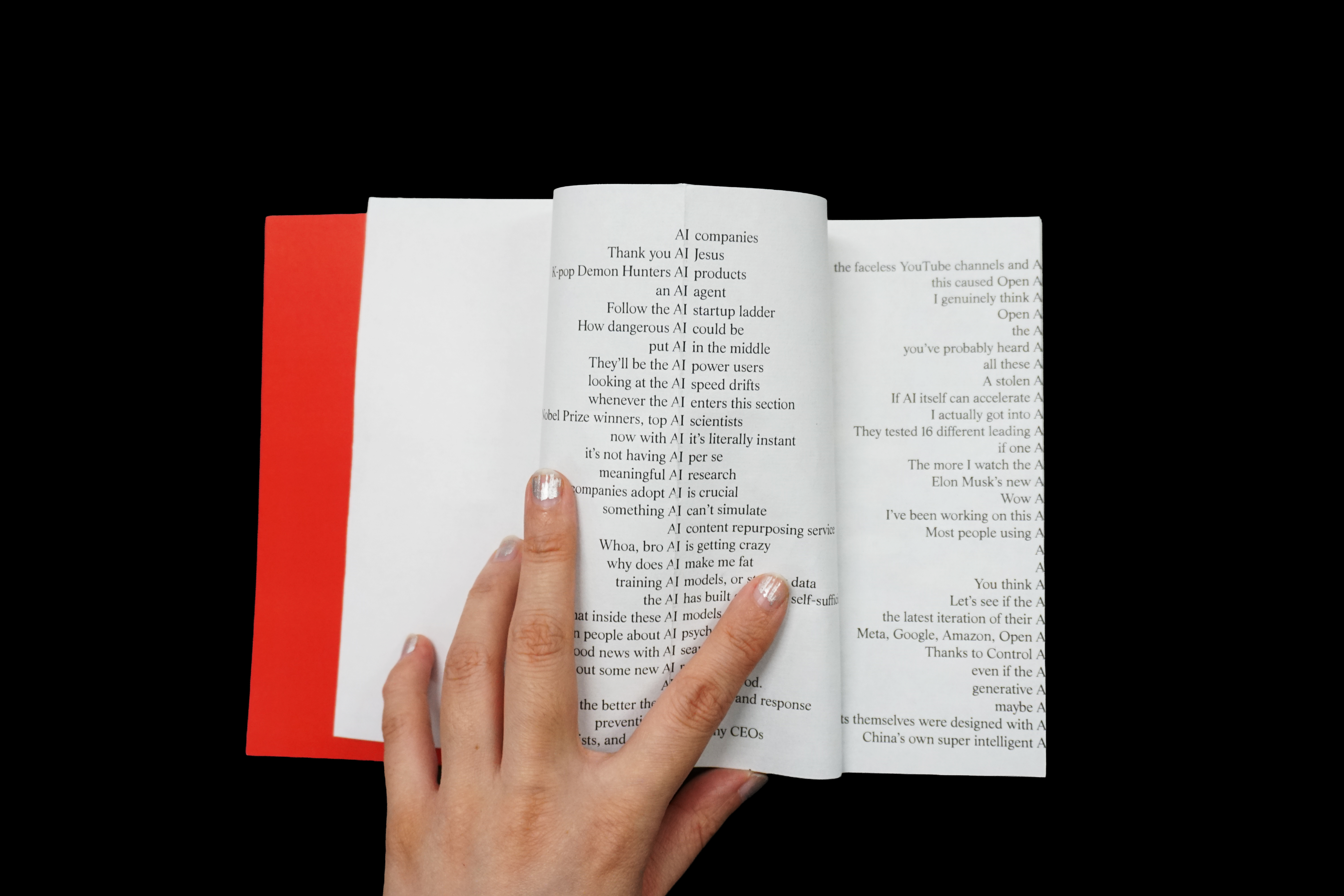 a book with a red cover against a black background. The interior spread shows two columns of text, each line containing a sentence fragment with "AI" as the pivot point — the left half of each sentence ends with "AI" and the right half begins after it, creating a visual caesura down the center of each page. 