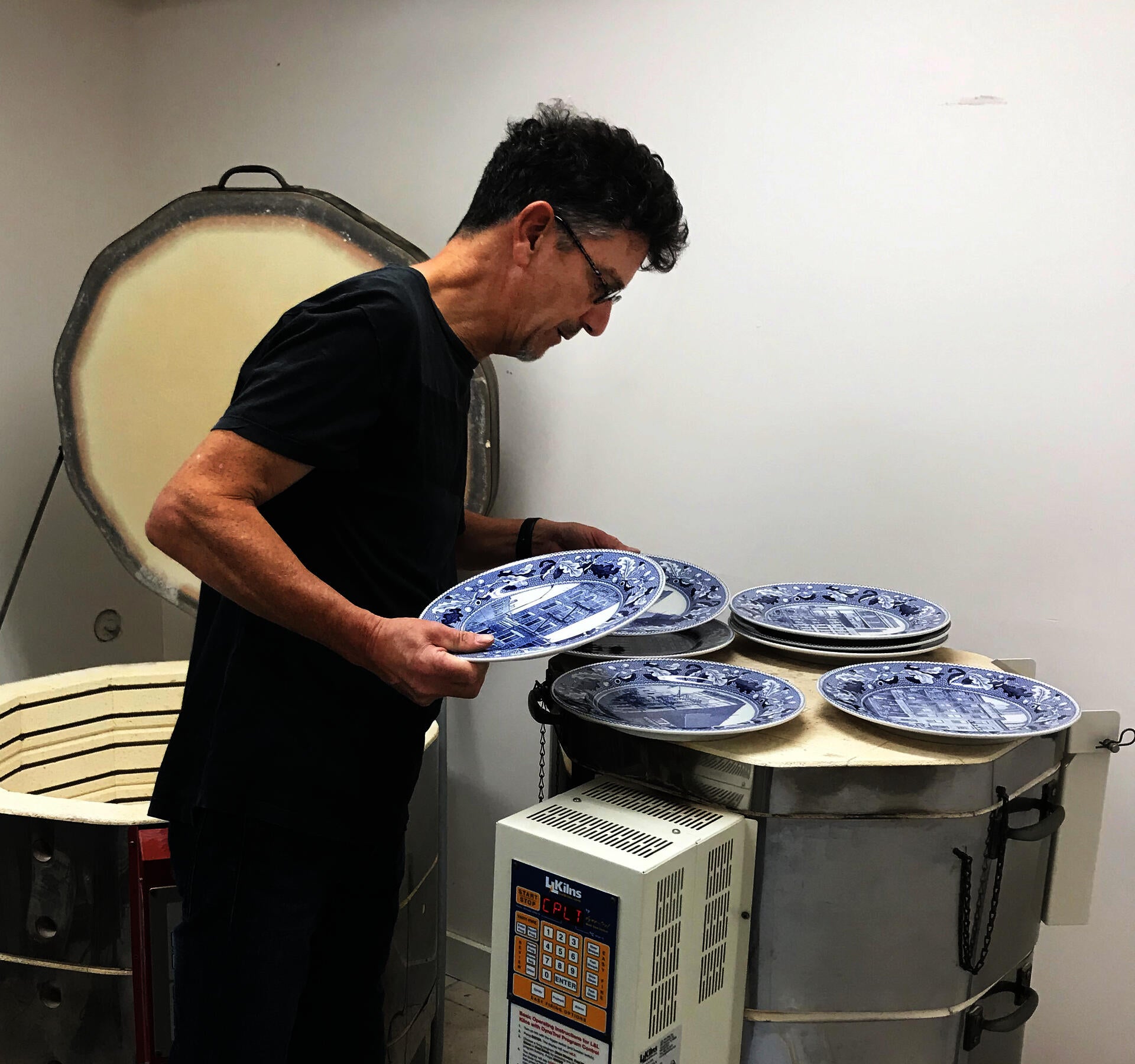Paul Scott examines his blue and white transferware plates after they have come out of the kiln