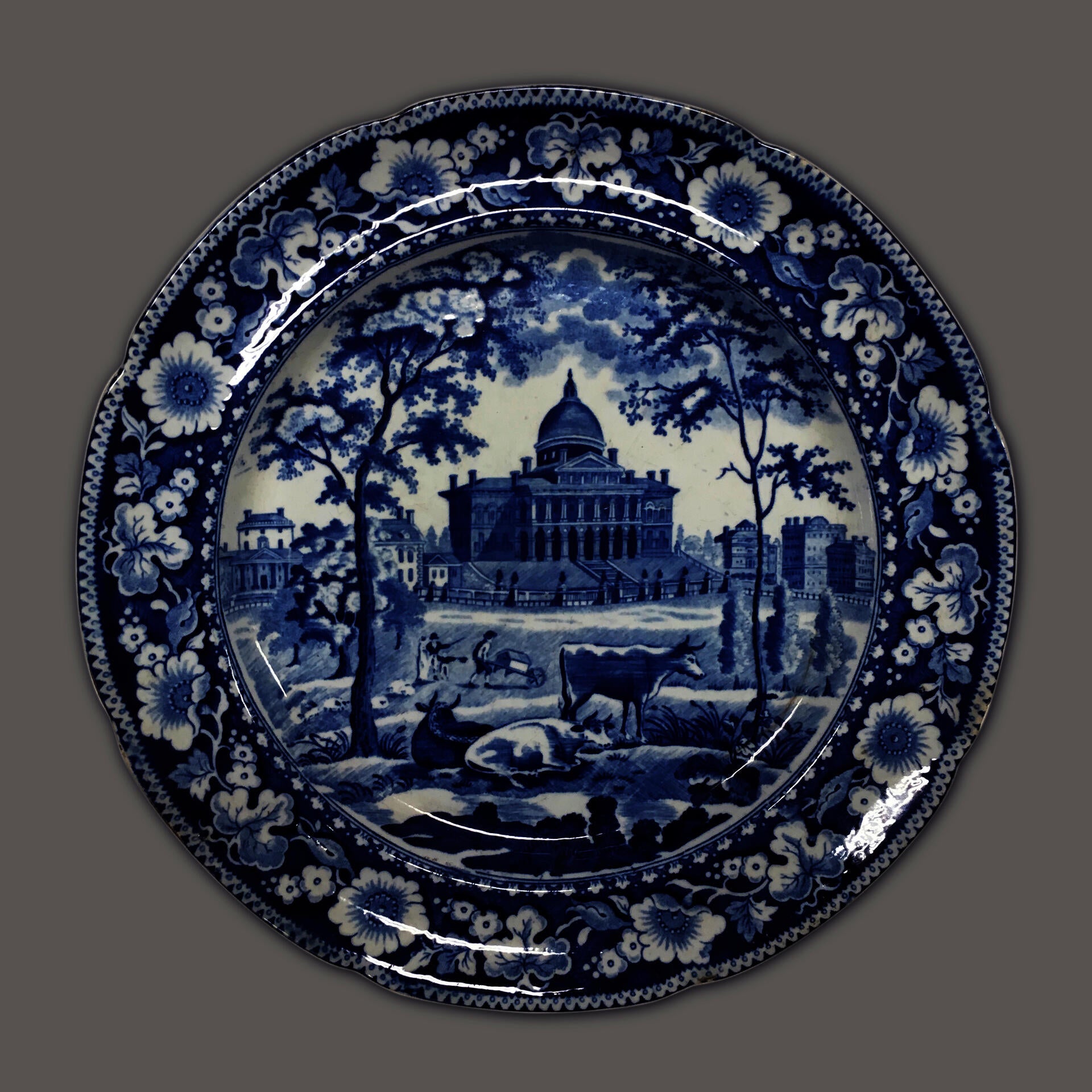 blue and white transferware plate depicting the Boston State House with cows in the foreground