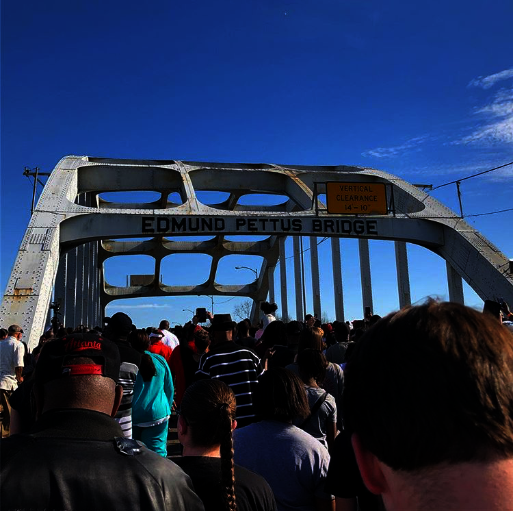 a crowd of people marching across the Edmund Pettus Bridge