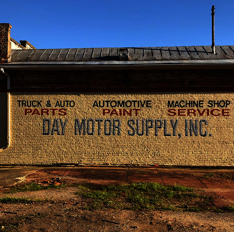hand painted sign for a motor supply company on a brick building