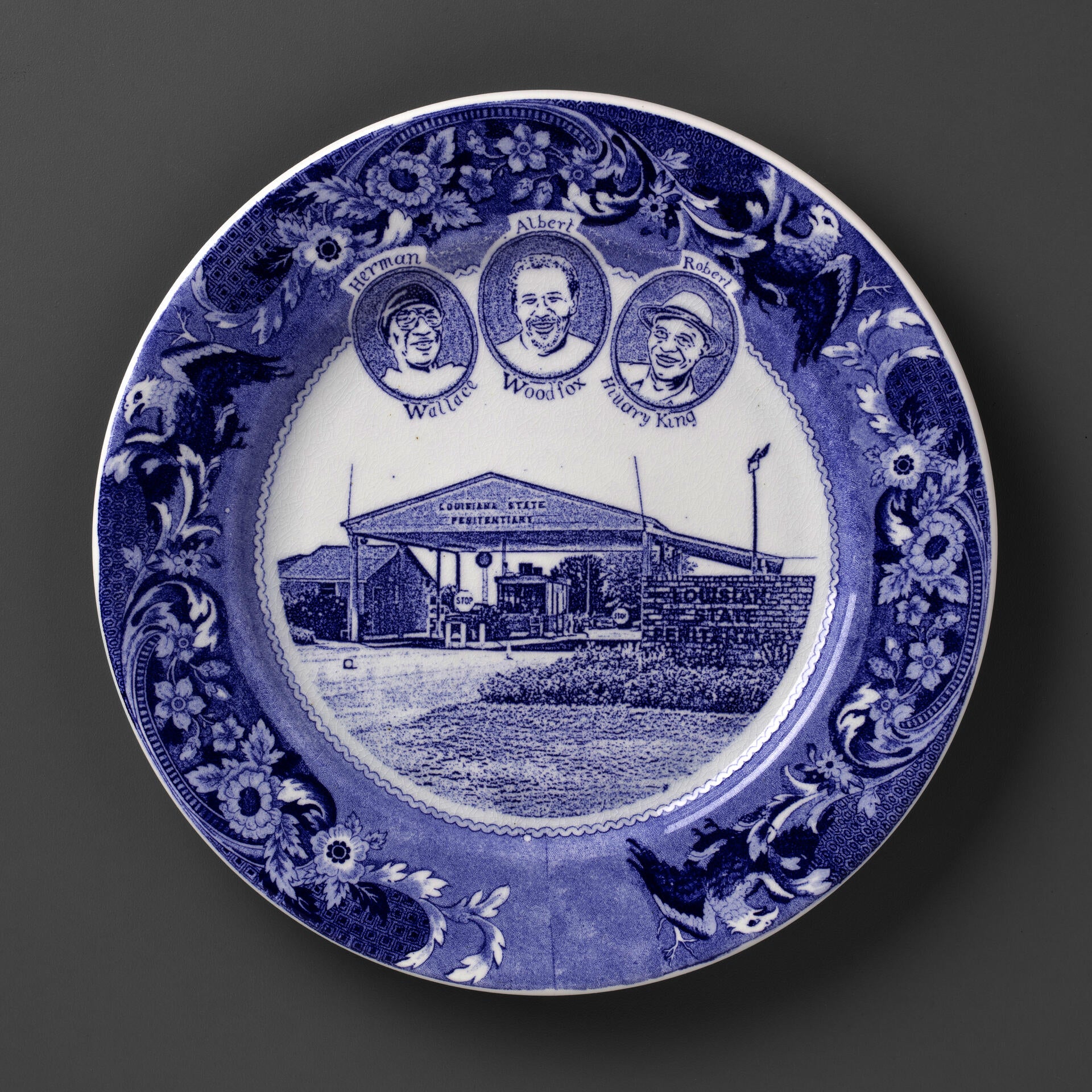 blue and white transferware plate depicting the Angola 3, and the Louisiana State Penitentary