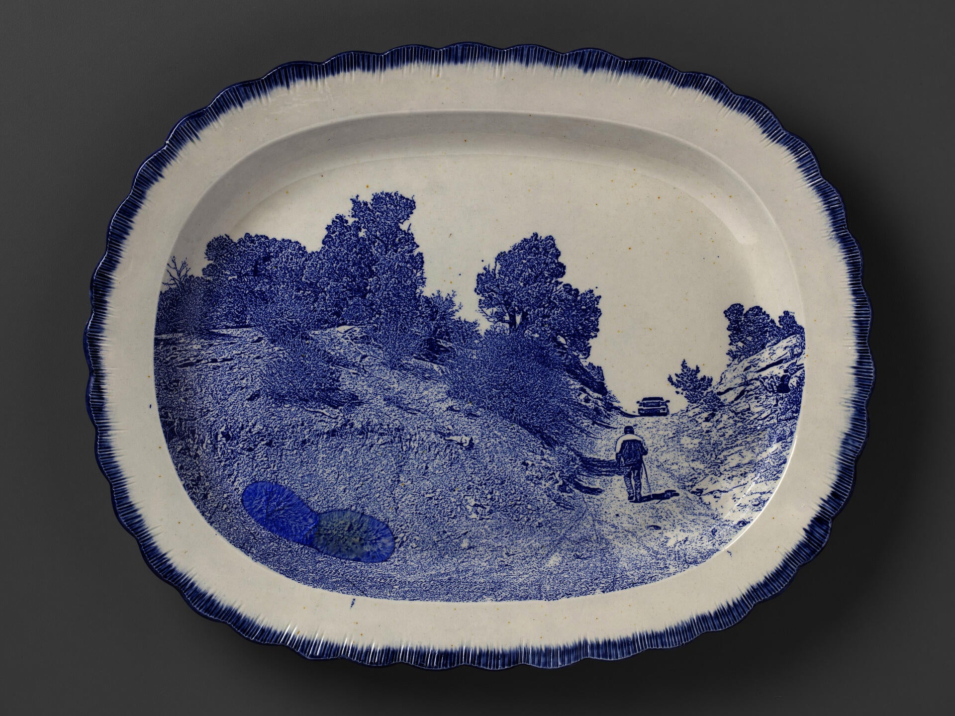 blue and white transferware plate depicting Timothy Benally walking up the road up to one of the Cove uranium mines, with melted Uranium glass