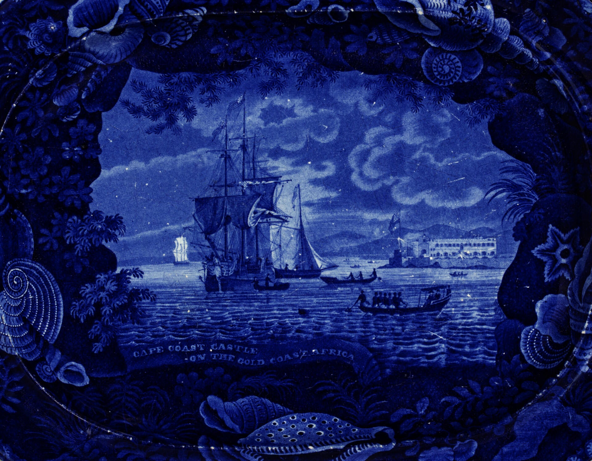 detail of the Cape Coast Castle platter, blue and white transferware depicting a slave ship with a shell border
