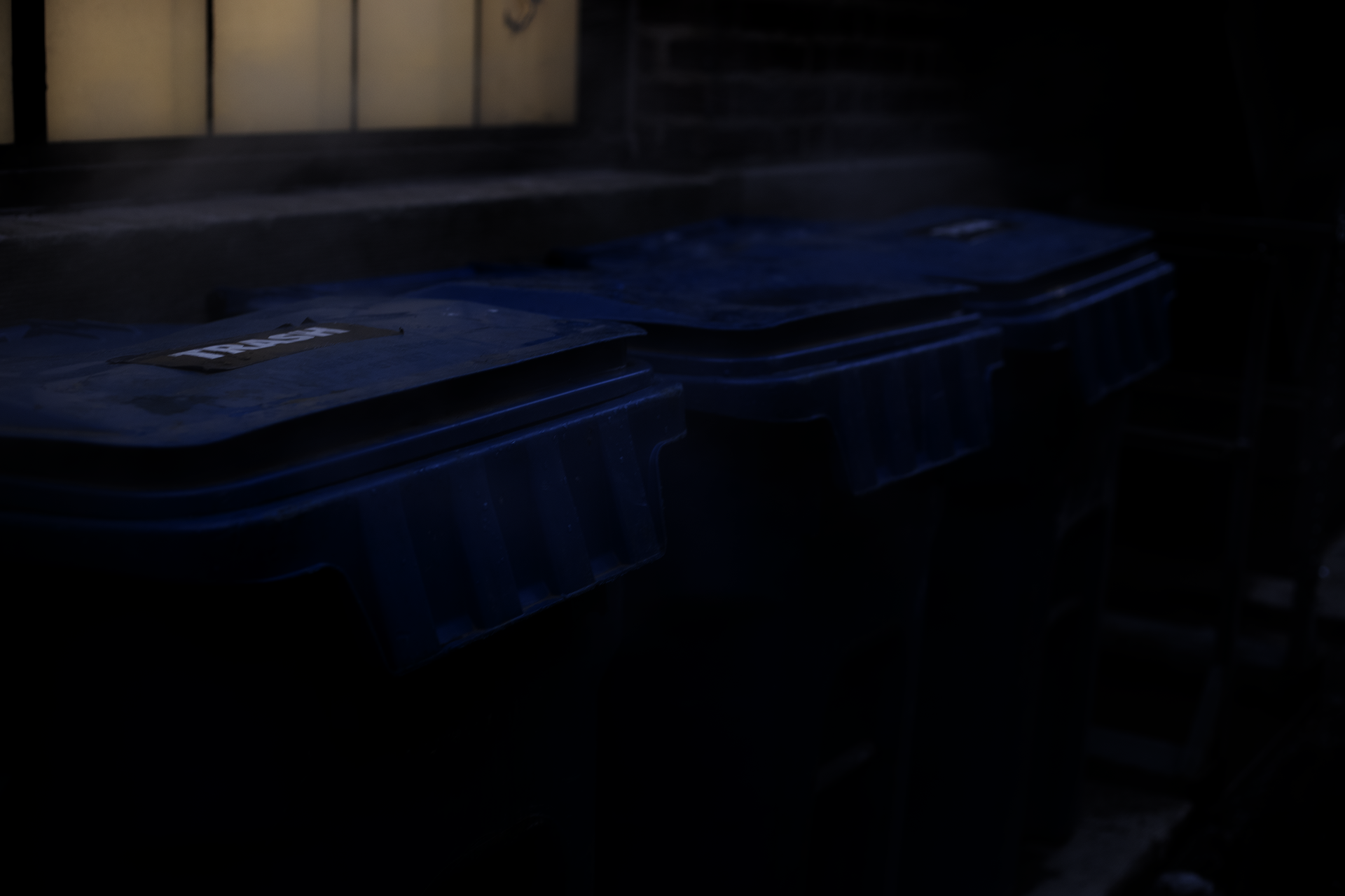 steam rises around three blue trash cans
