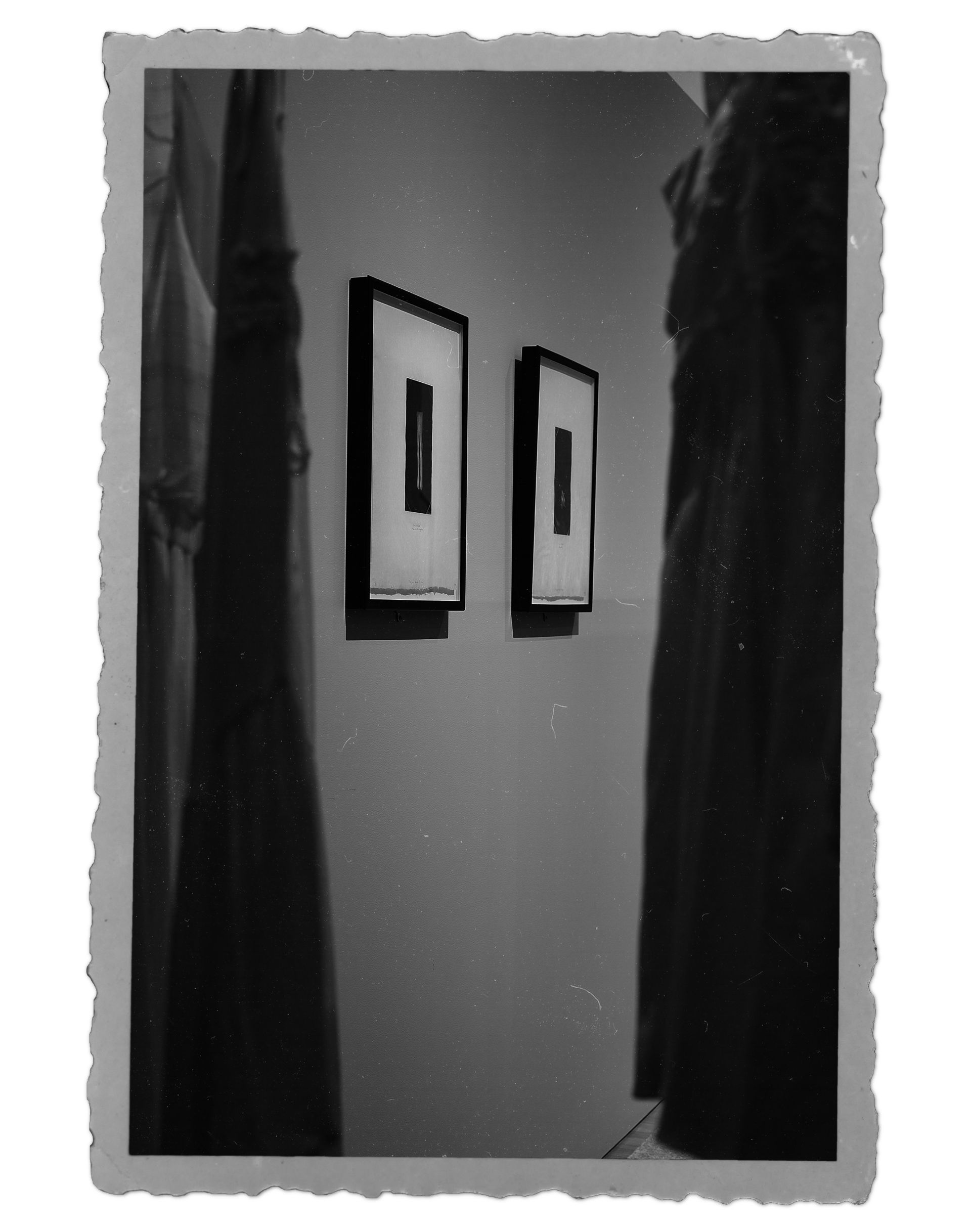 "Old" photograph of two prints by Milagros de la Torre, viewed through hanging white dresses