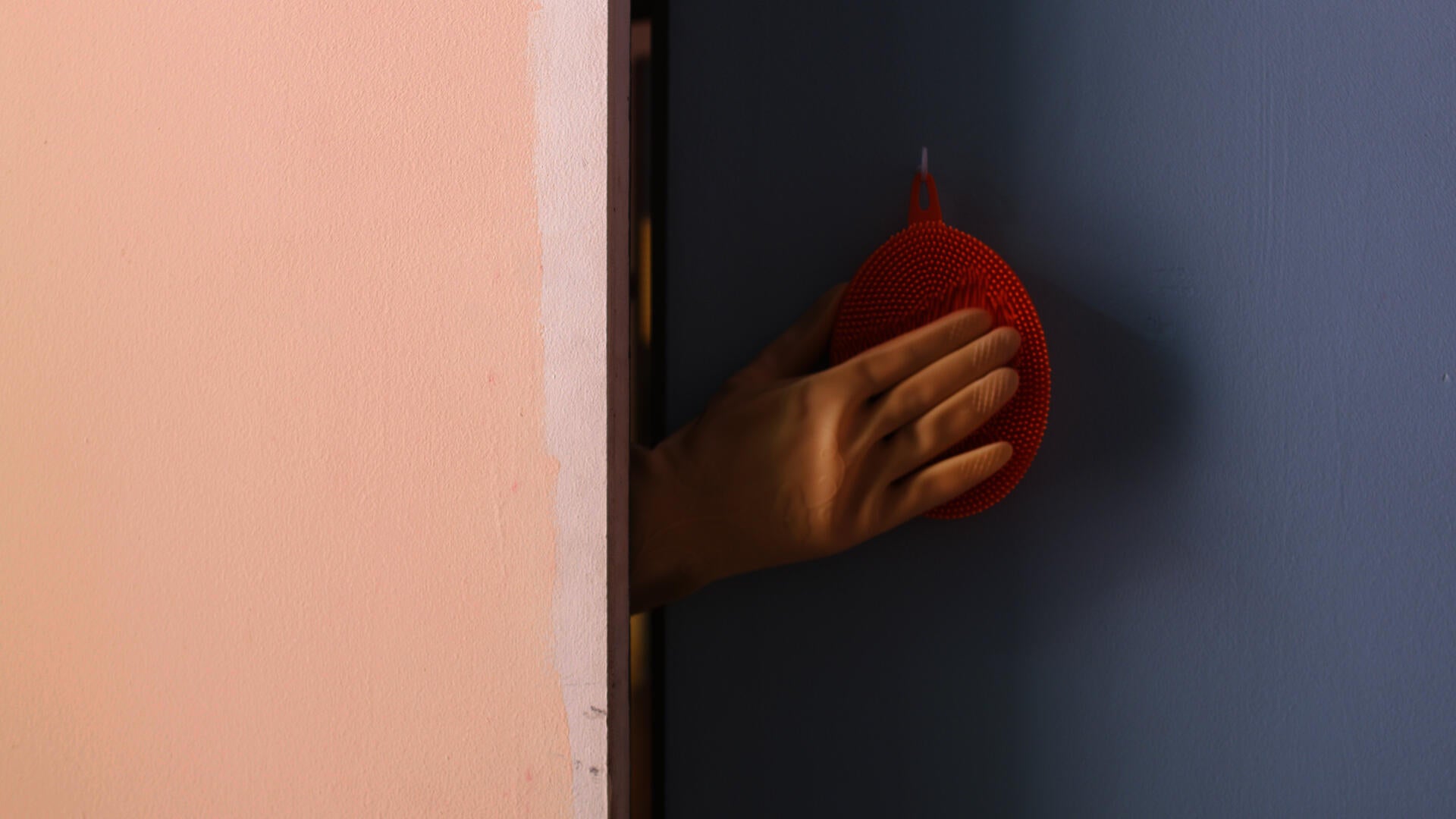 Untitled (Studio) still, gloved hand touching a silicone kitchen brush