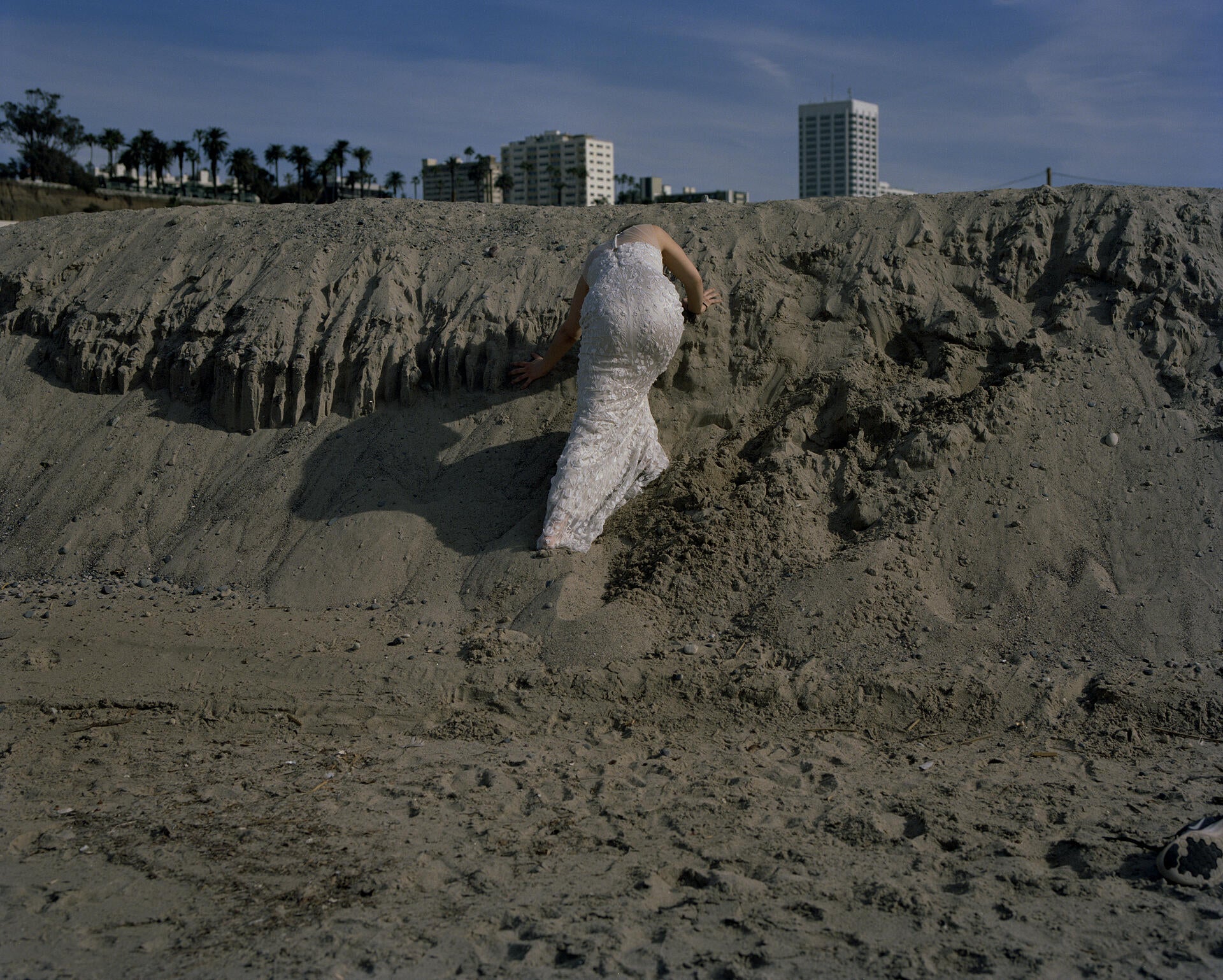 A woman climbing sand dunes in her wedding dress