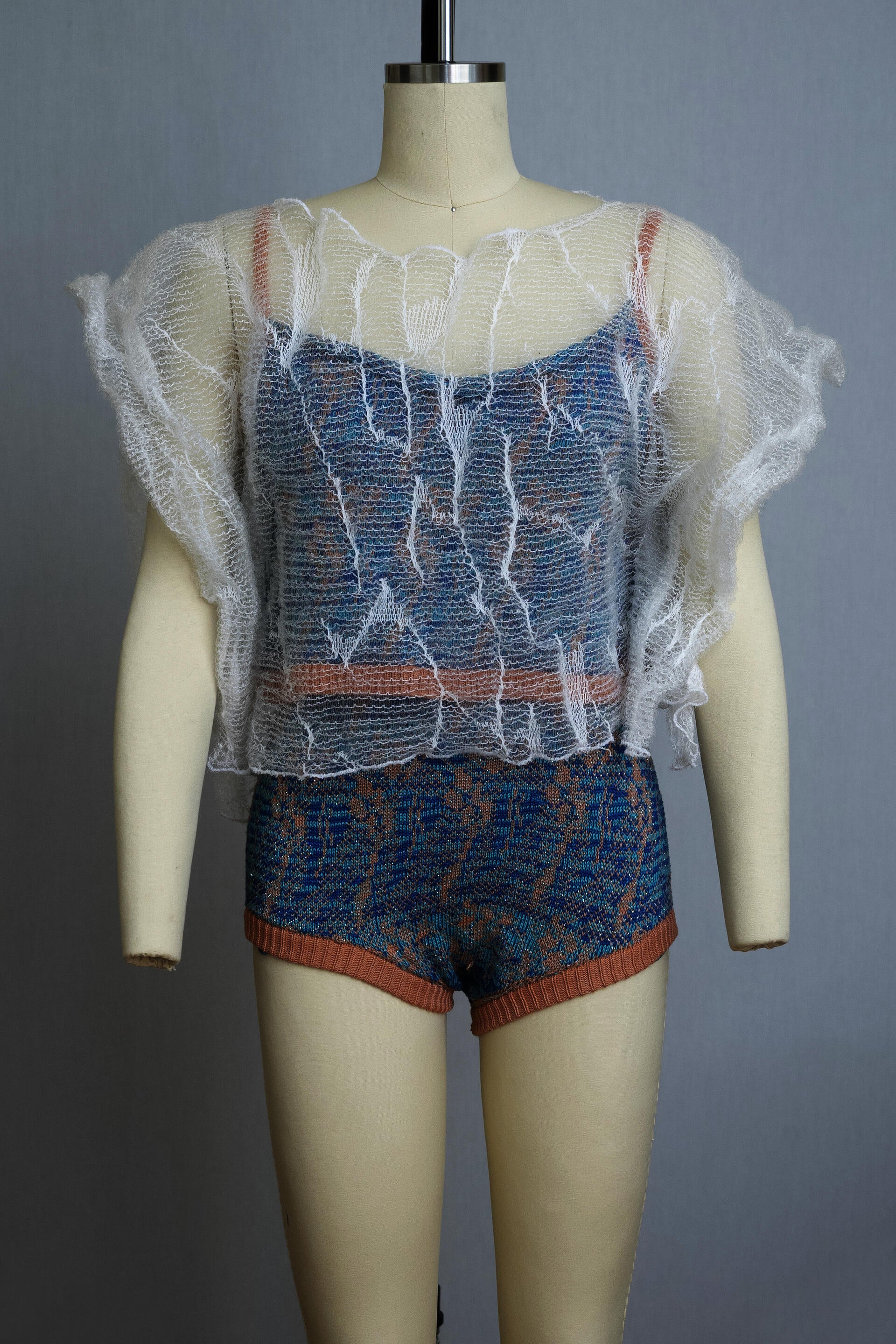 dress form wearing a knit playsuit in blues and pink with a sheer knit top