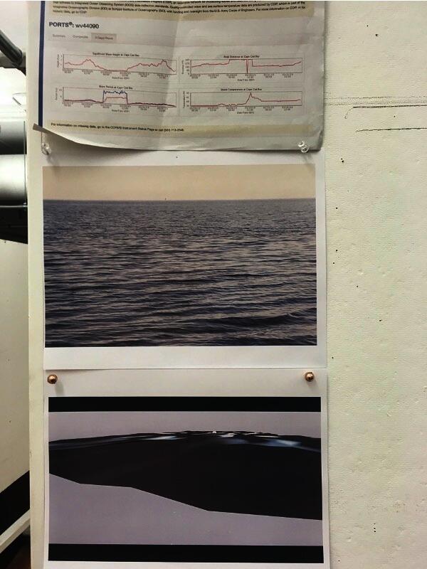 A scientific chart and pictures of waves are pinned to a wall.