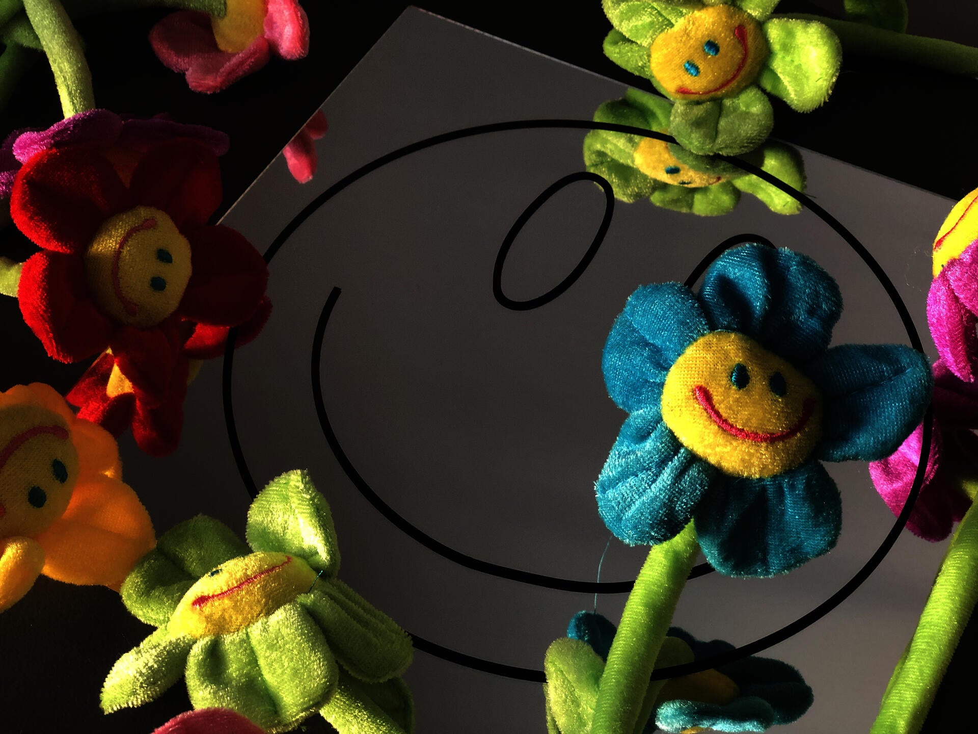Smiley face graphic on a mirror with plush smiley face flowers