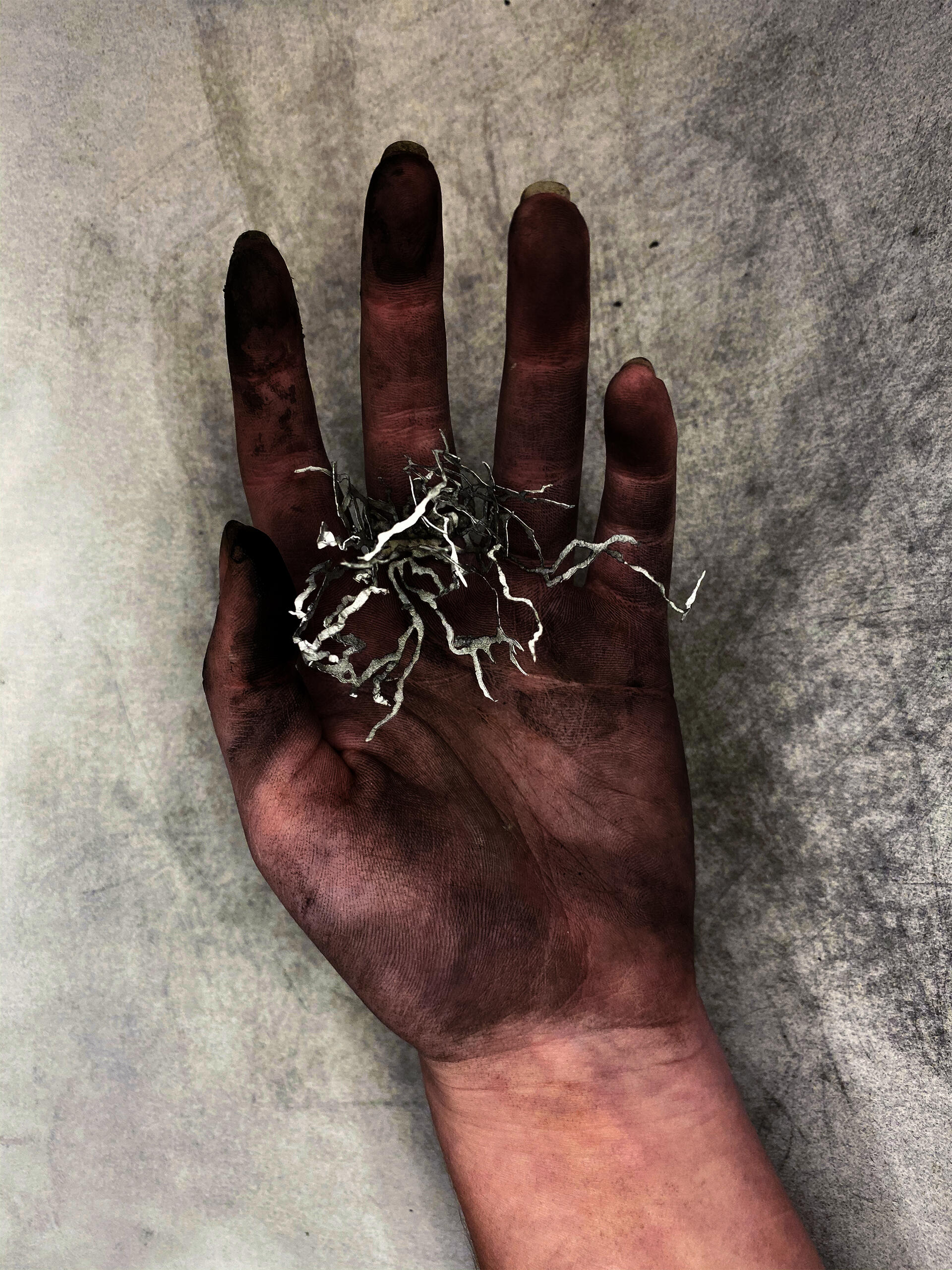 Hand covered in ash holding a small paper sculpture