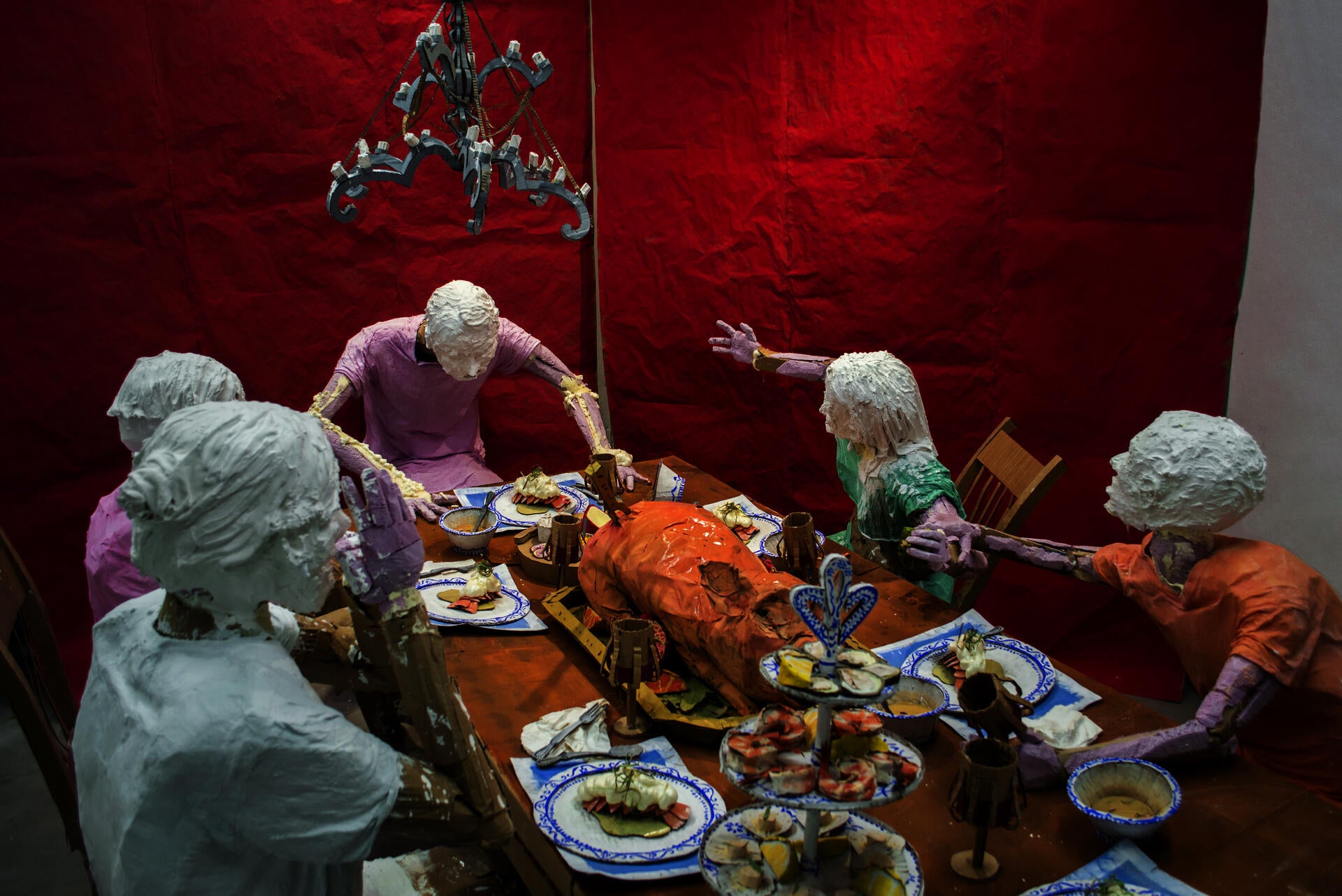 Installation sculpture of a group of people sitting around a dinner table.