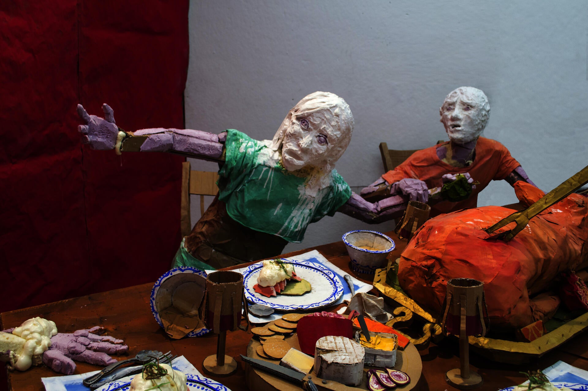 Installation sculpture of a group of people sitting around a dinner table.