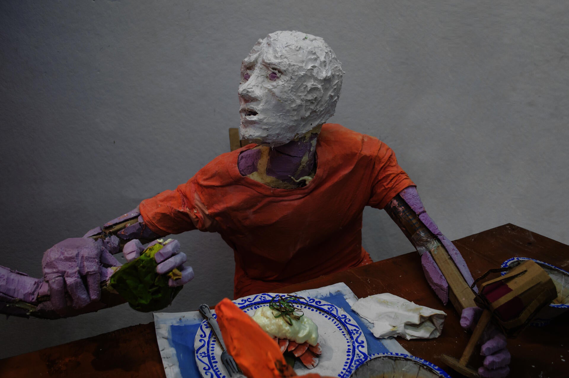 Installation sculpture of a group of people sitting around a dinner table.
