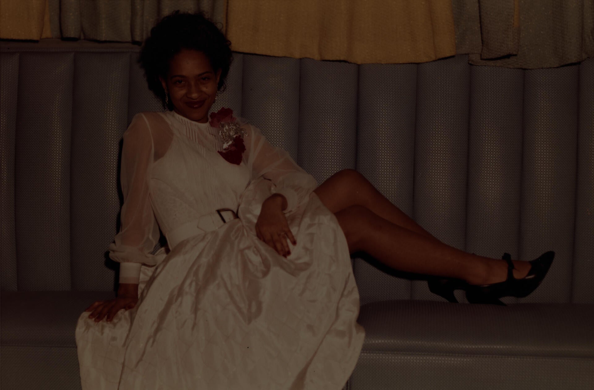 Color snapshot of a woman in a white dress on a grey sofa