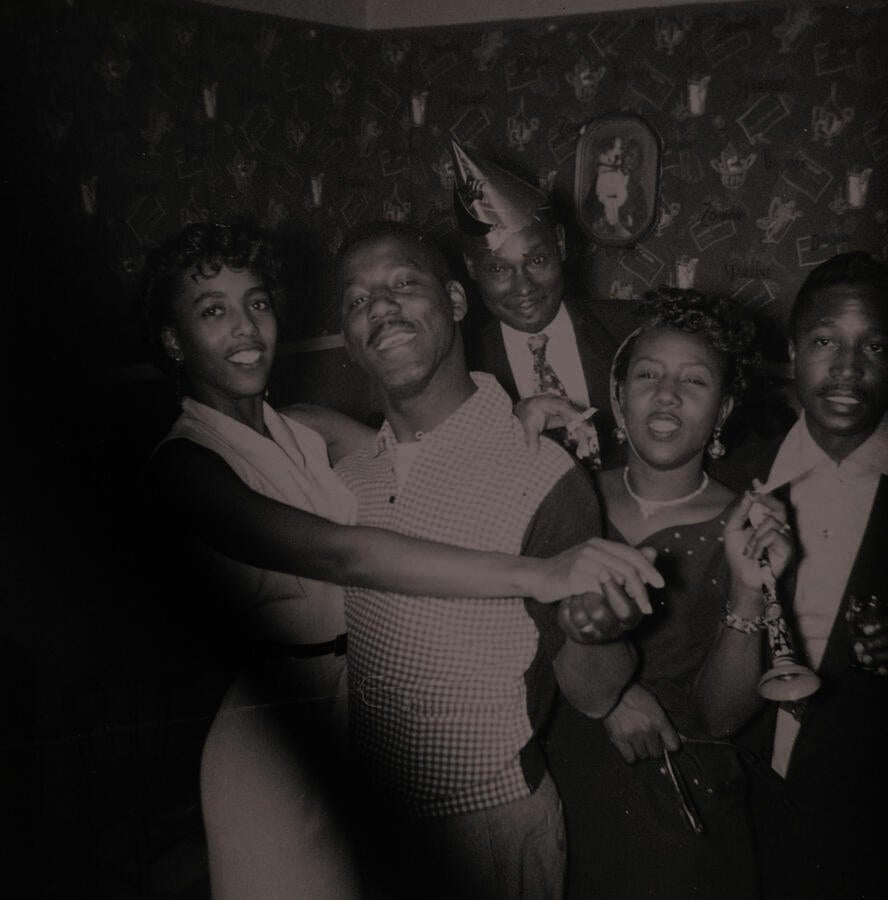Black & white snapshot of a five young Black folks at a party