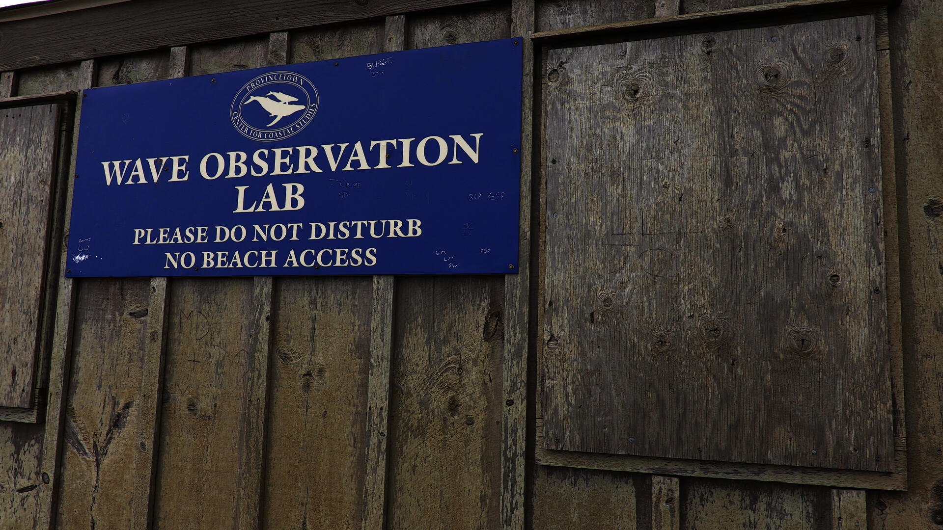 A sign on a wooden shed that states WAVE OBSERVATION LAB.