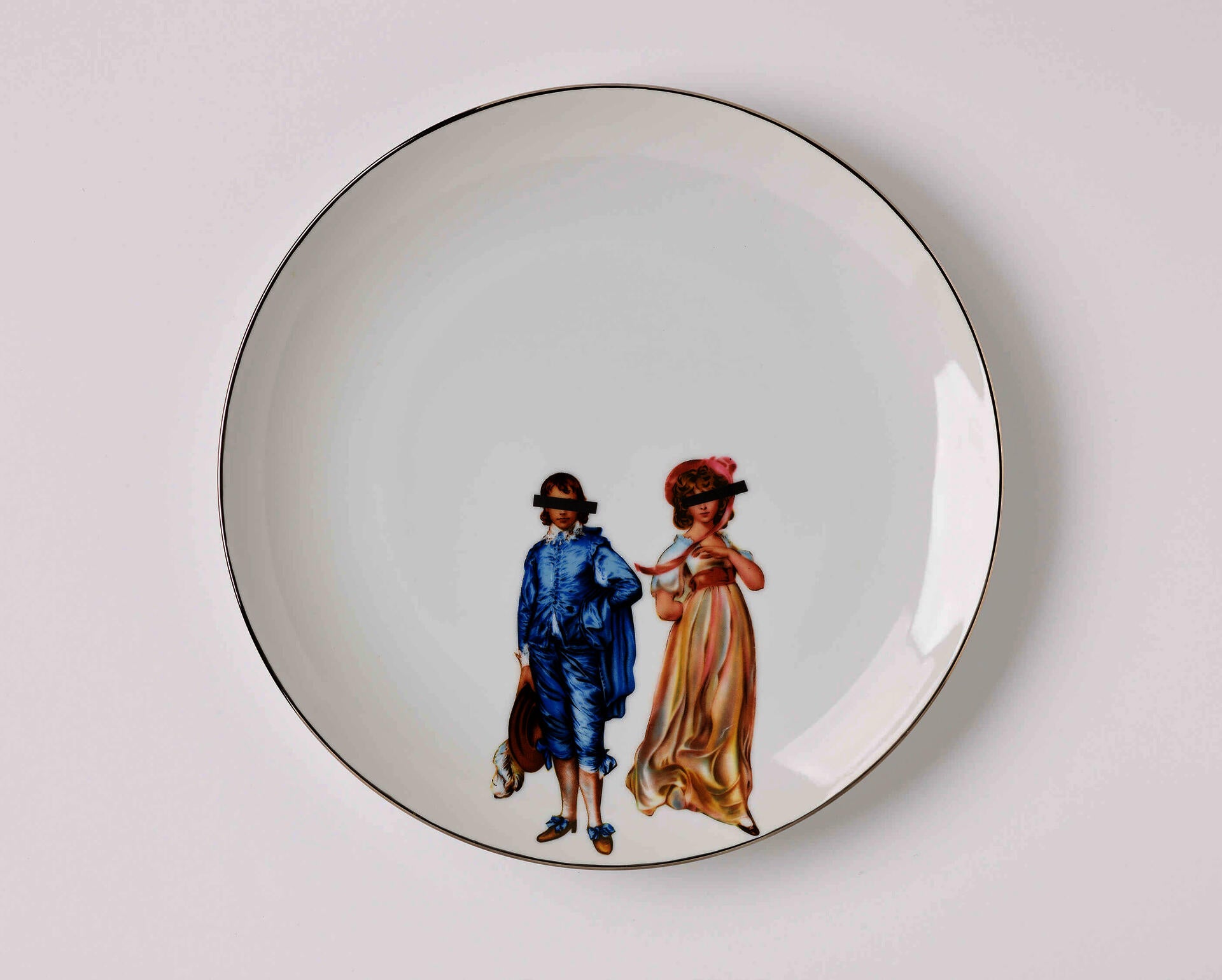 A white ceramic plate with an illustration of a Victorian-style man and woman with black bars covering their eyes