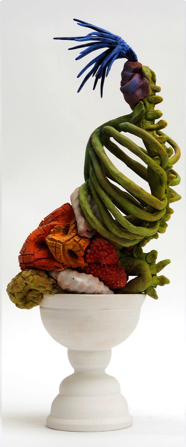 A thrown ceramic cup form with a skeletal abstraction on top. 