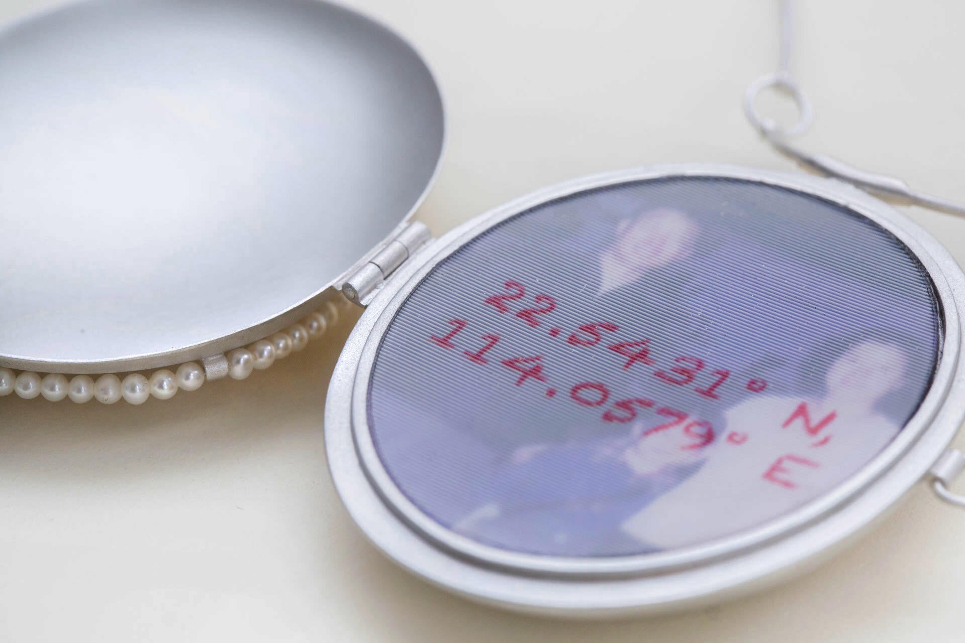 22.5431° N, 114.0579° E is a locket necklace, with lenticular print encased in the middle. 