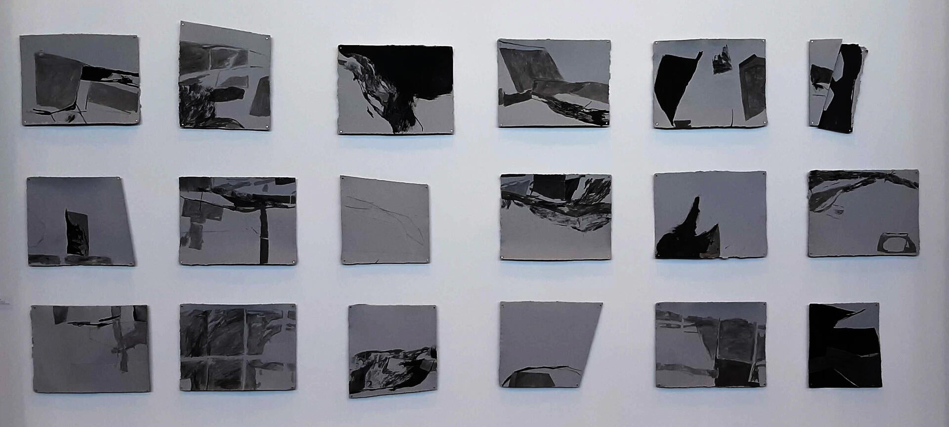 6 x 3 grid of grey blocks with black and grey ink washes and lines, abstract but referencing building shapes, architectural geometries and maps