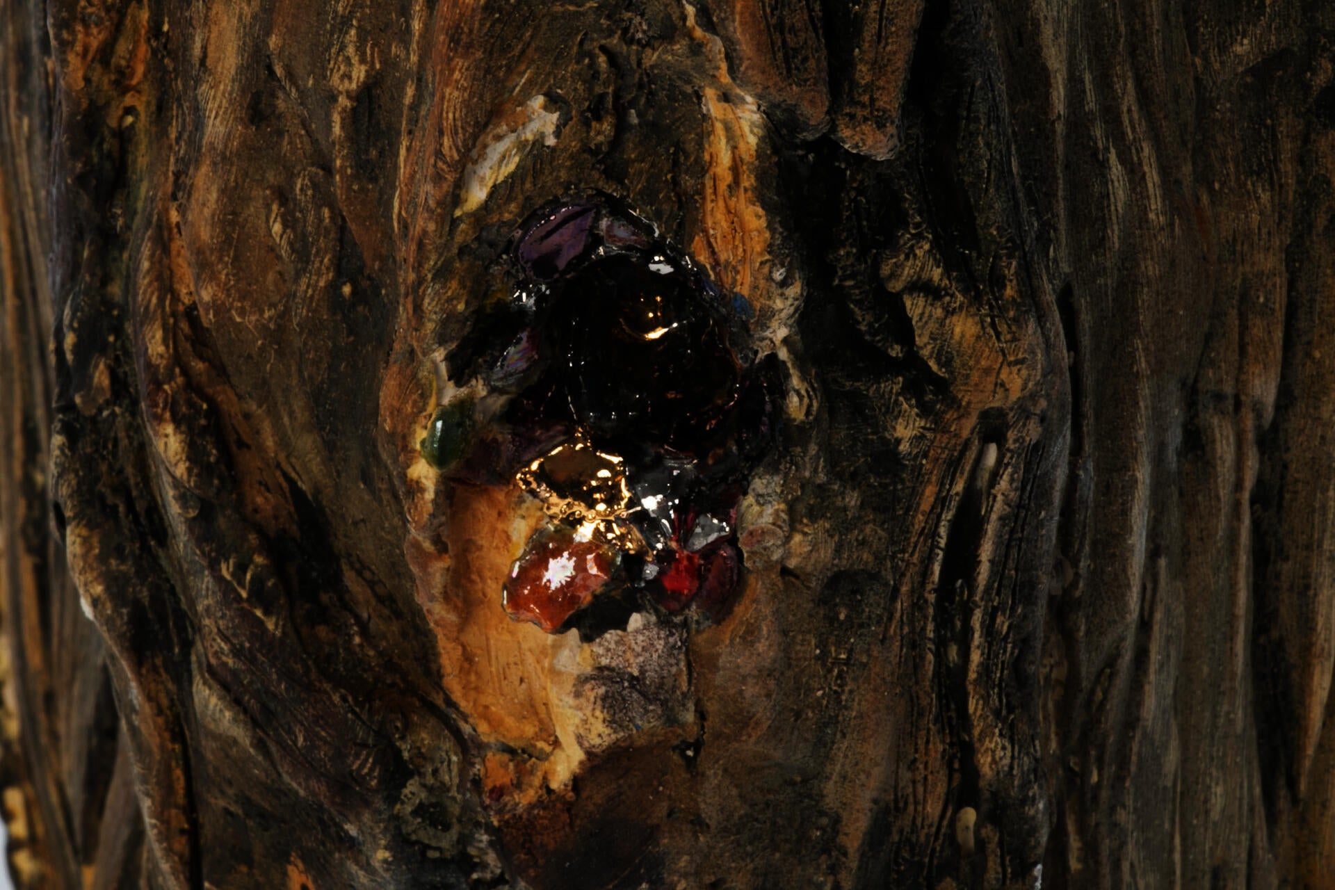 Detail of ceramic firewood sculpture depicting hole with sparkling confetti spilling out in wood.
