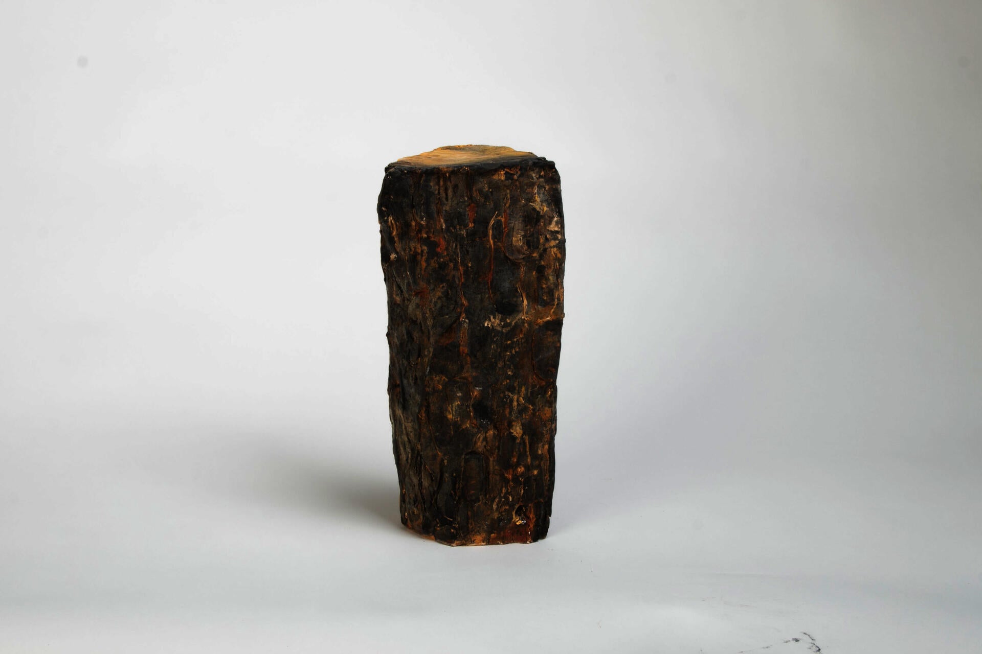 Ceramic sculpture resembling fire wood with shiny confetti spilling out of cracks and knots in wood.