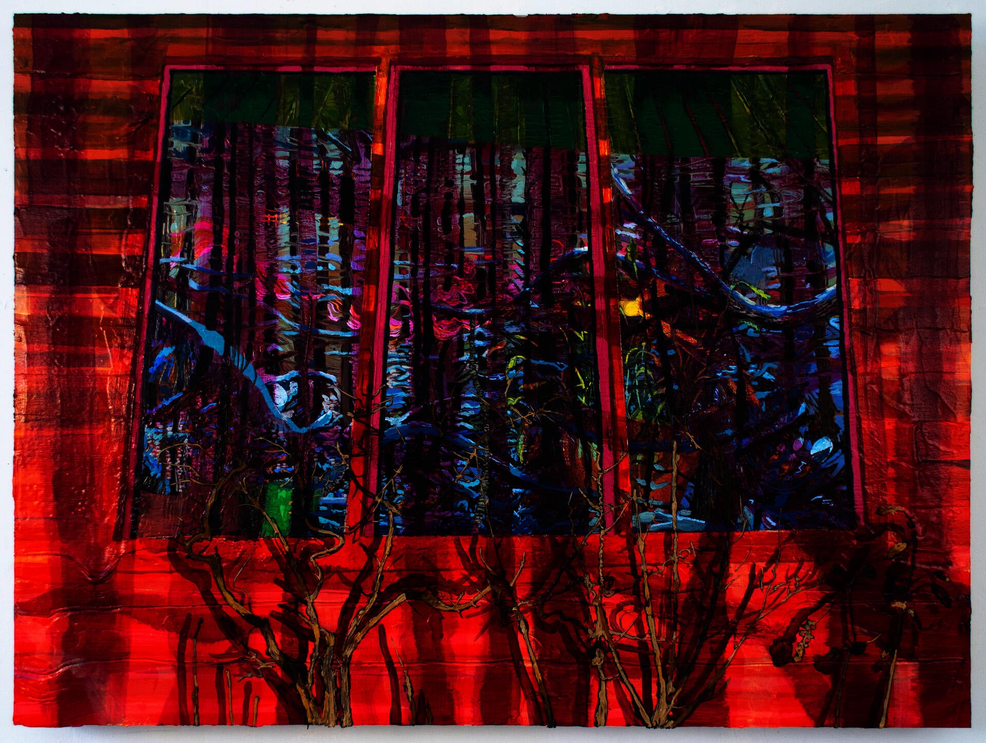 A exterior window of a red barn reflects a winterscape of snow covered trees