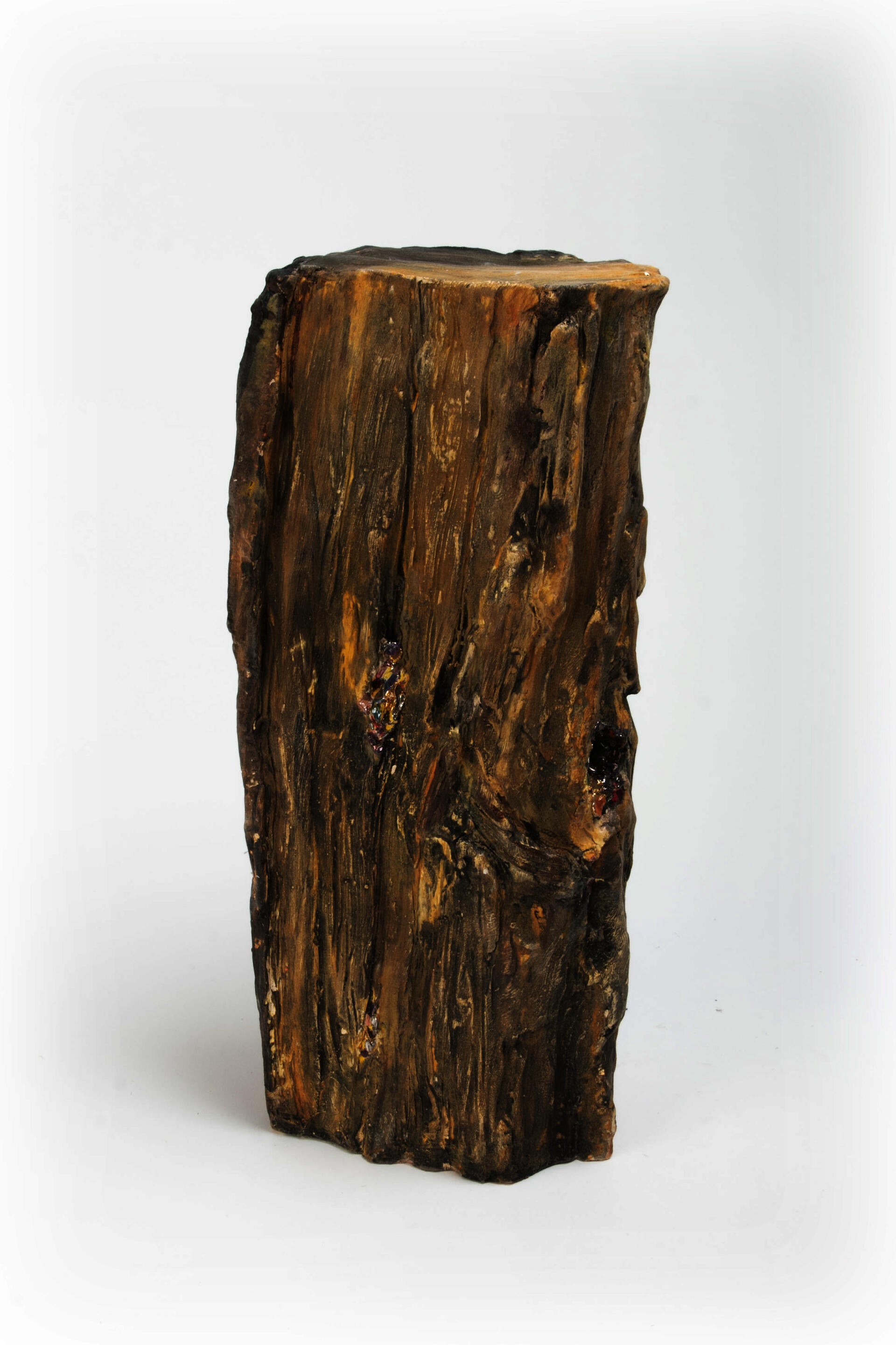 Ceramic sculpture resembling fire wood with shiny confetti spilling out of cracks and knots in wood.