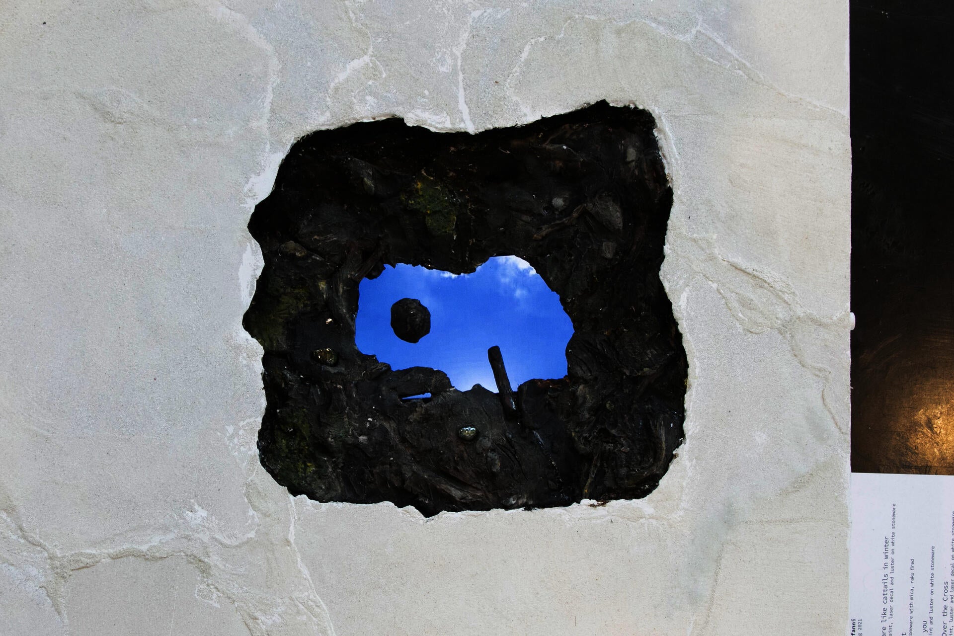 Ceramic sculpture of mud puddle with video playing of the sky.
