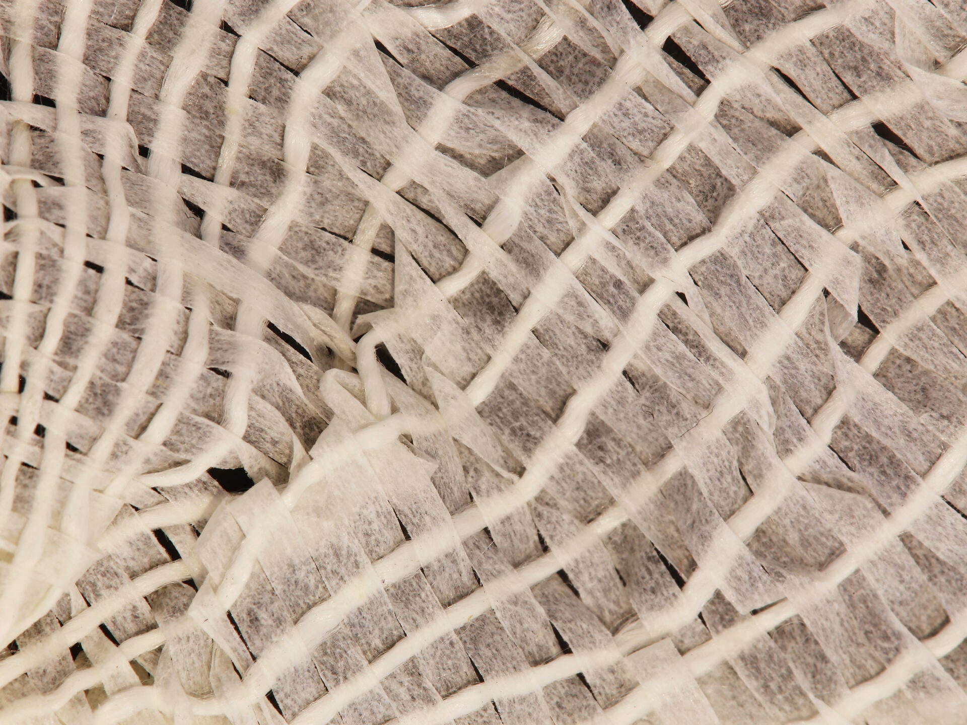 Up close shot of the weaving which is made of white waxed silk and paper strips. There are very small gaps in the weave. 