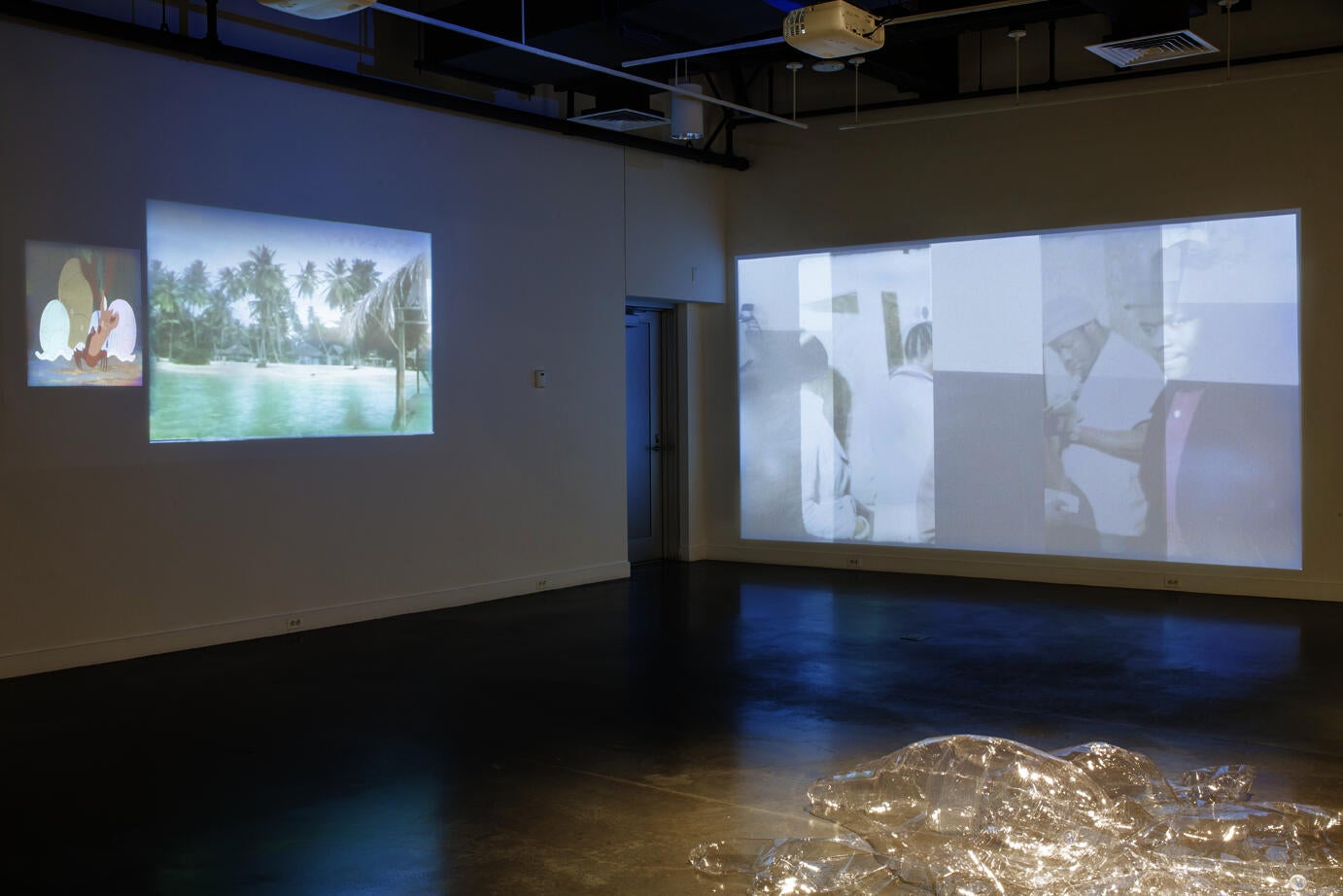 gallery interior; two walls display faintly projected images