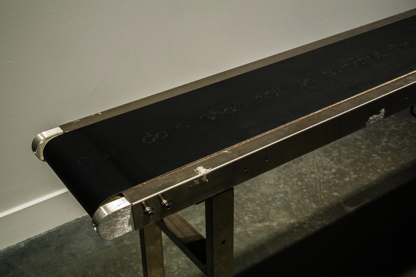 metal structure with black leather stretched across it in a long strip. Incised into the leather are the words "Our days shall not be sweated"