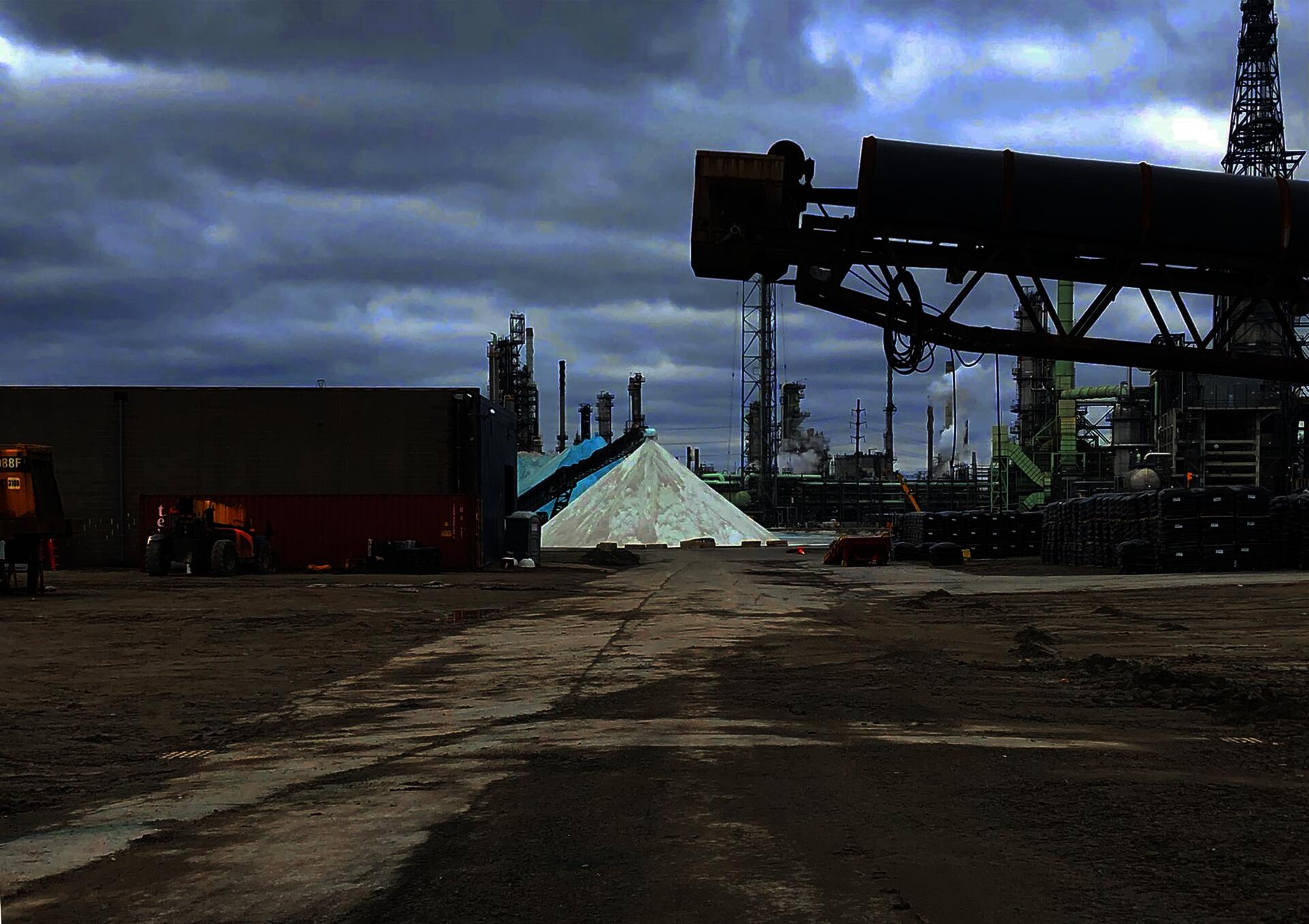 A photograph of some of the facilities of the Detroit Salt Co. including mining equipment, heavy machinery, and stockpiles of road salt.