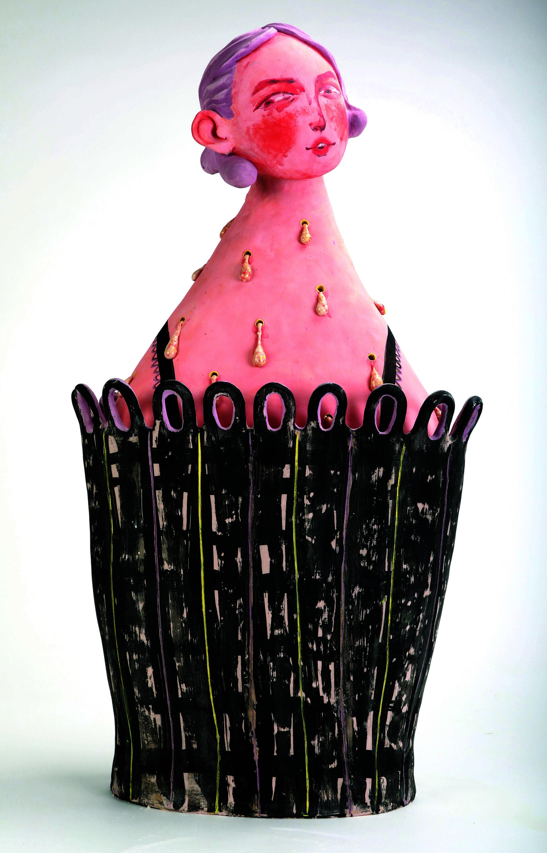 A ceramic figure with pink skin, purple hair, and a "knowing" expression.
