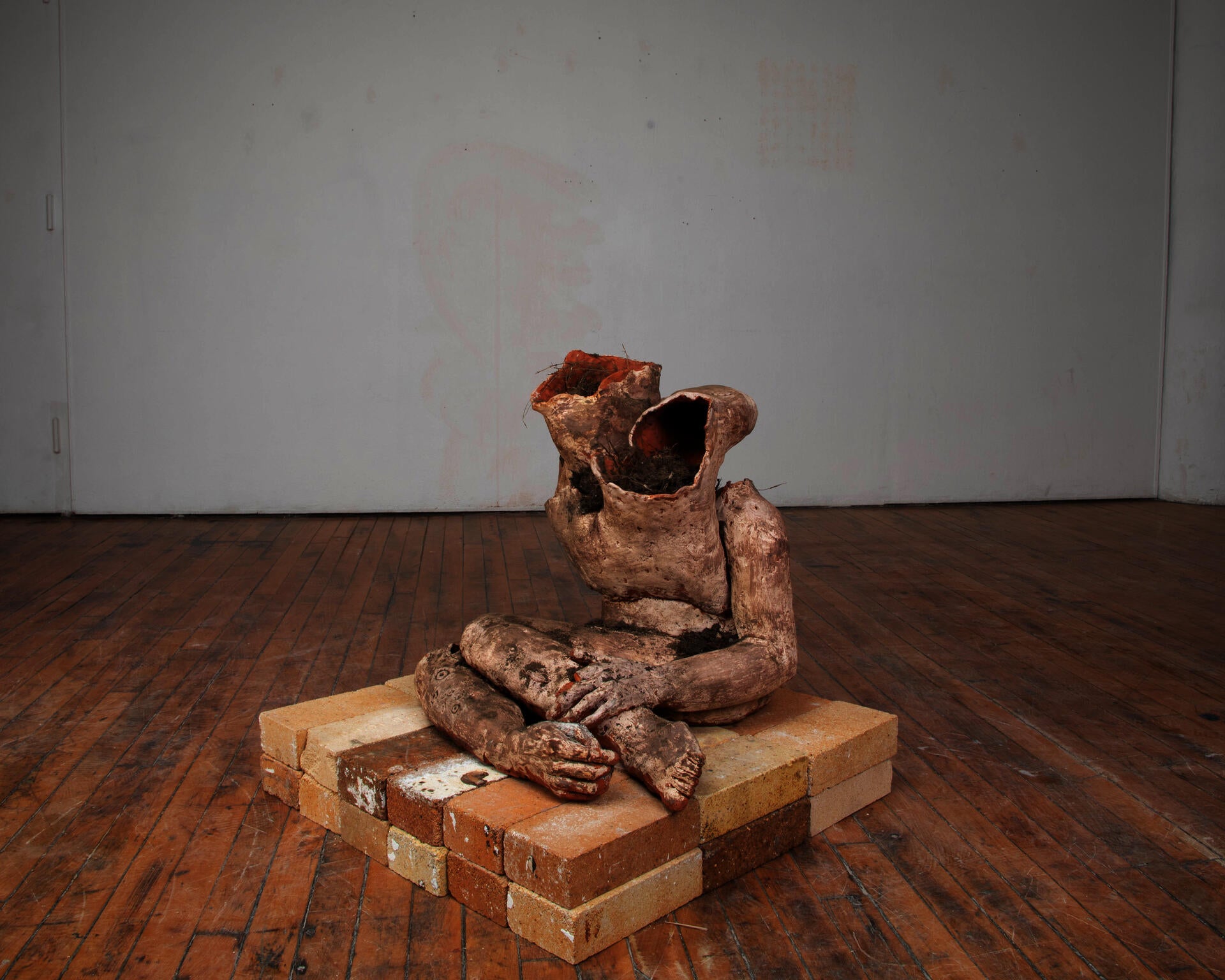 An abject terracotta body filled with soil seated on bricks