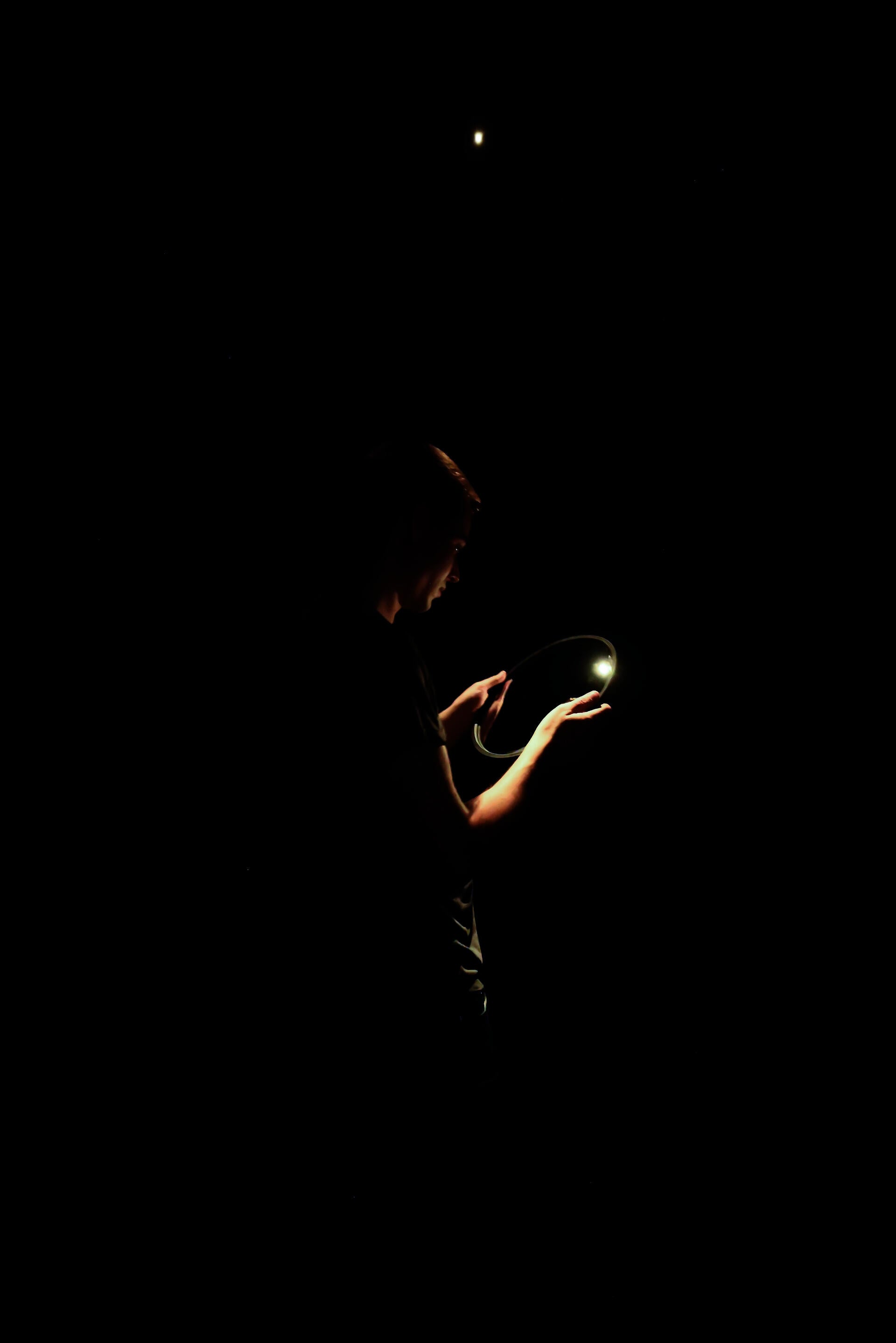 A dark void with the artist standing in the center illuminated.