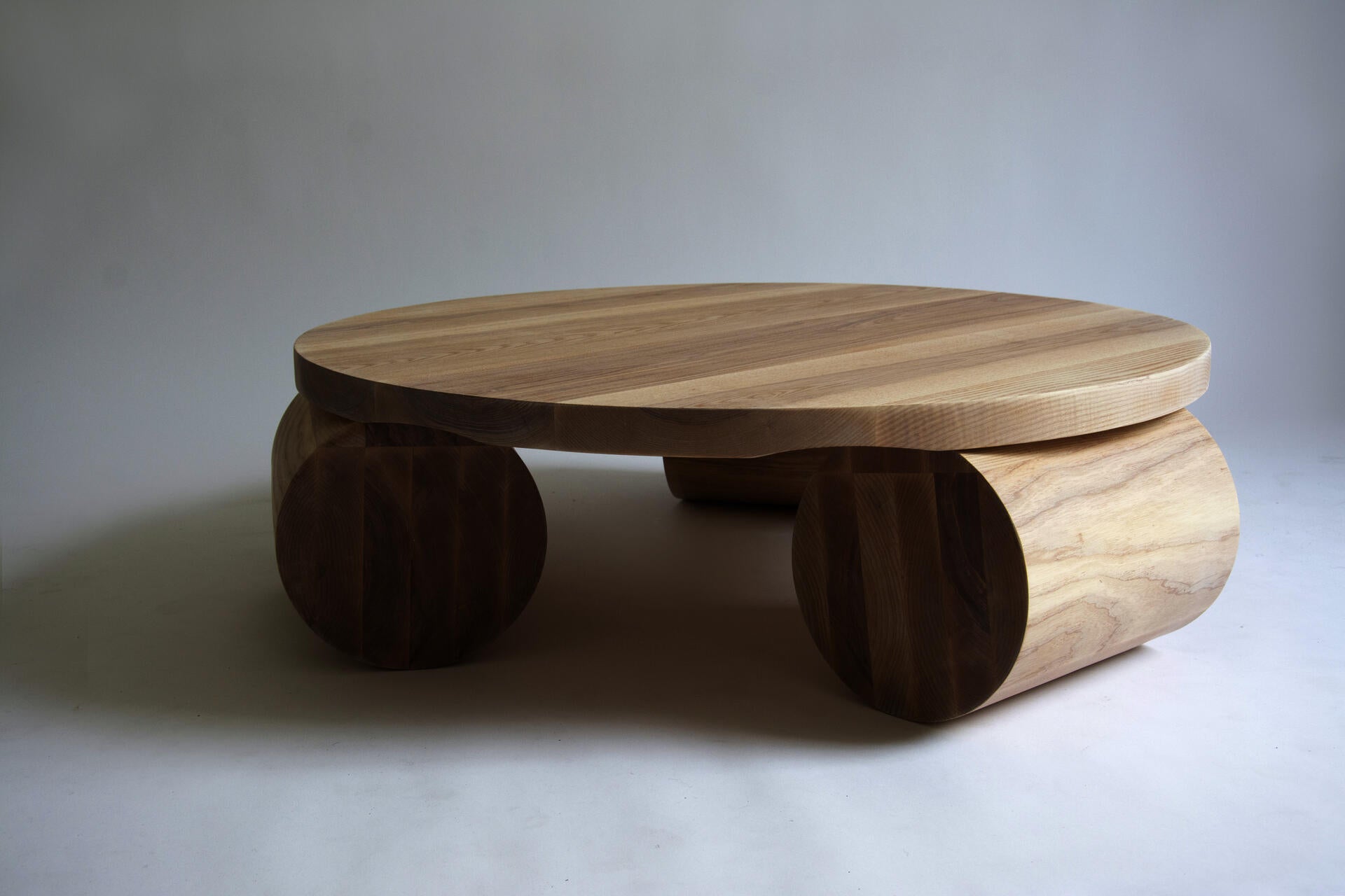 A large wooden circular top sits on top of three cylindrical legs.