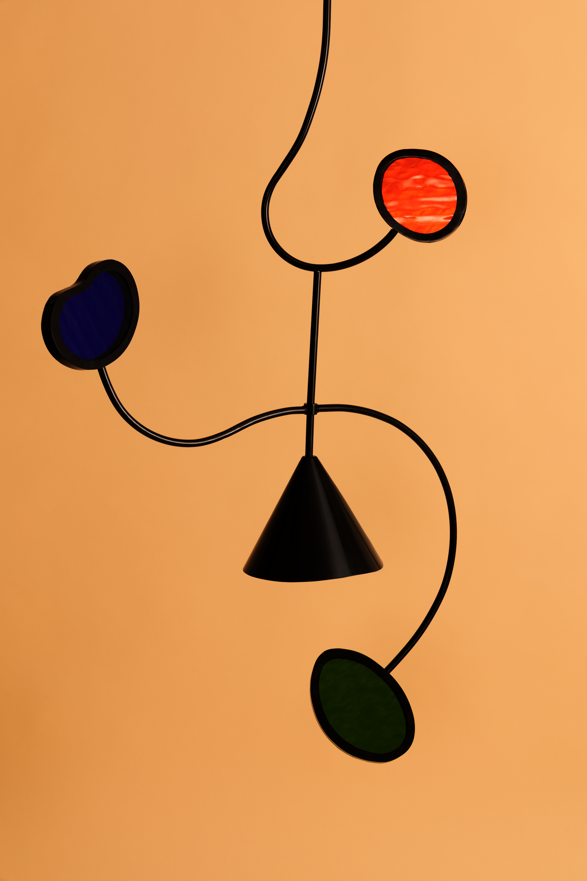 A Wavering Line Mobile is made of balanced bent steel and framed stained glass.