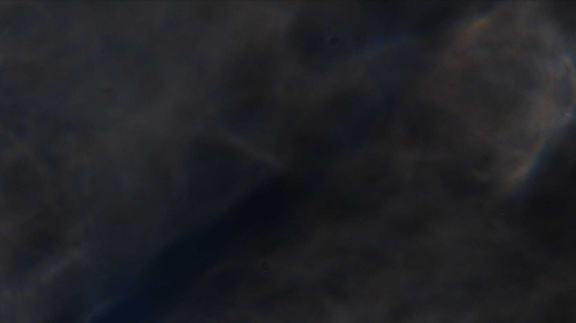a film still of blues and whites, something like sunlight on water, the shape of something unknowable emerging beneath