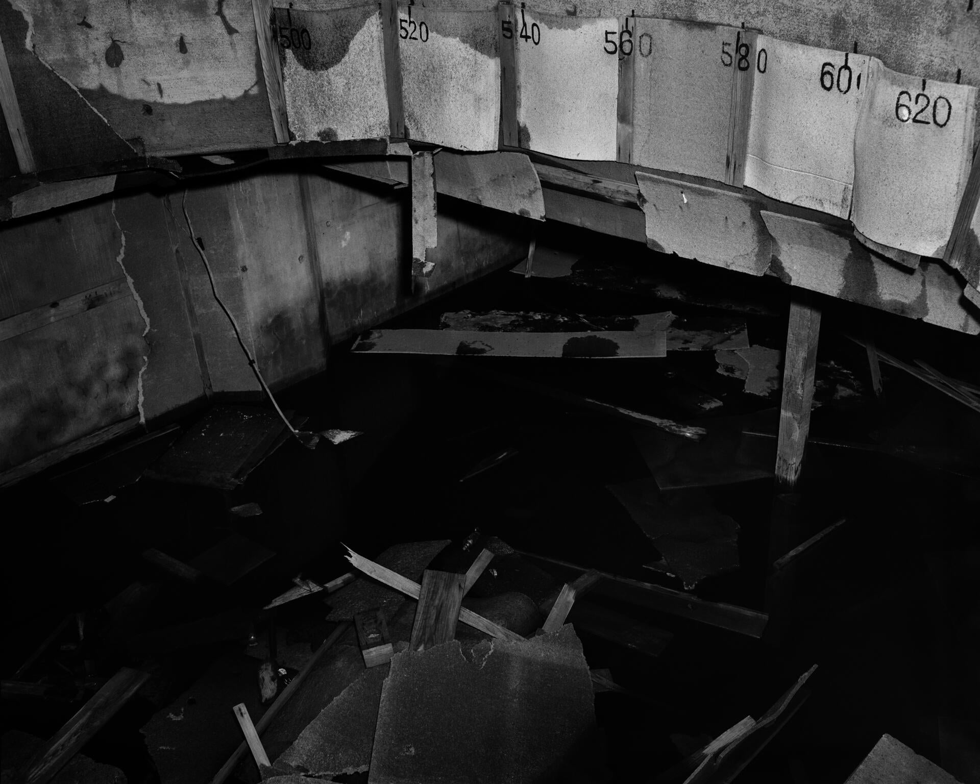 A black-and-white flash-lit photograph of a flooded enclosure, captured by the United States military at the end of World War II in the Pacific.