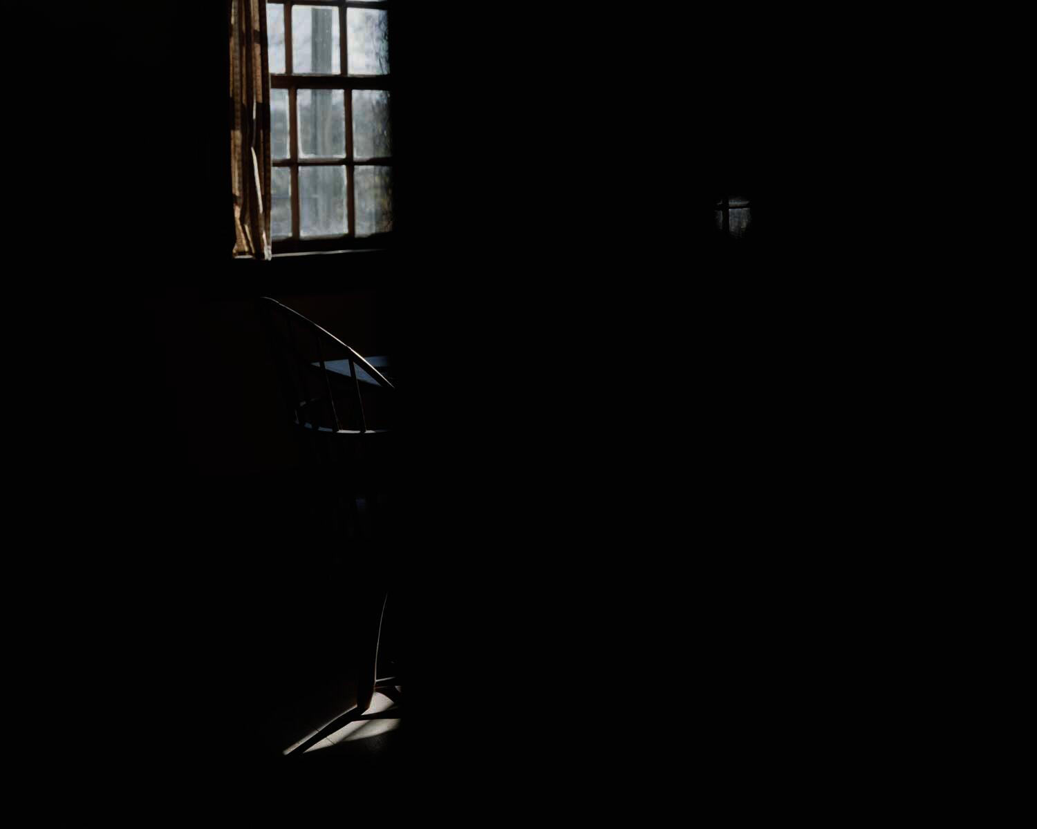 Shadowy image, one chair on left of frame.