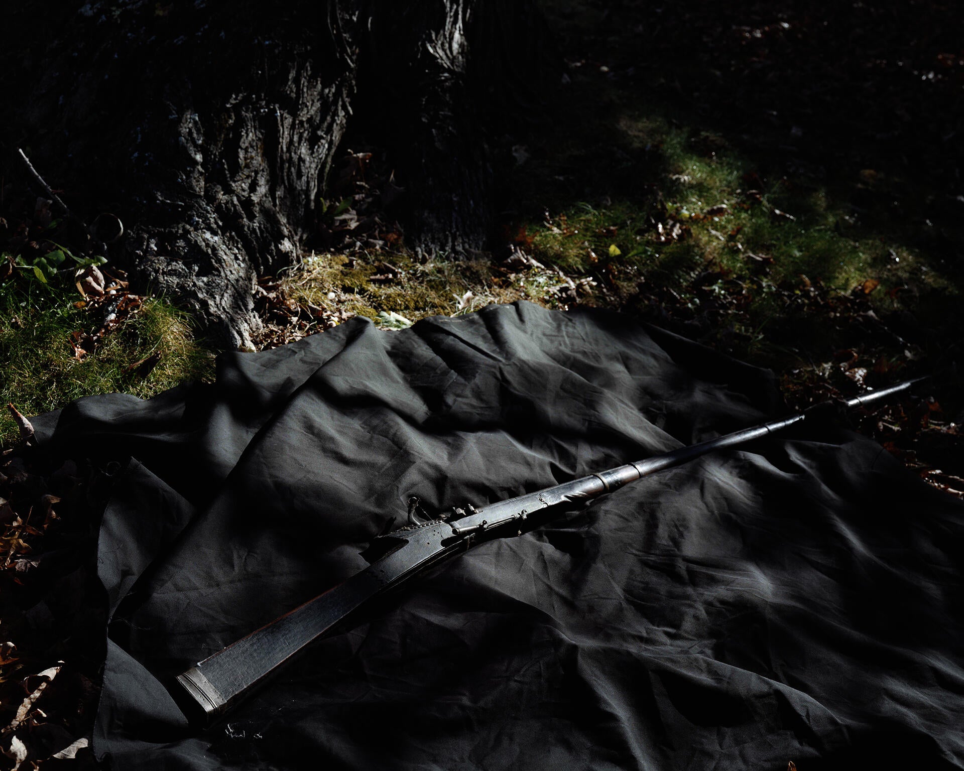Photograph of a rifle laid on a piece of fabric on grass.