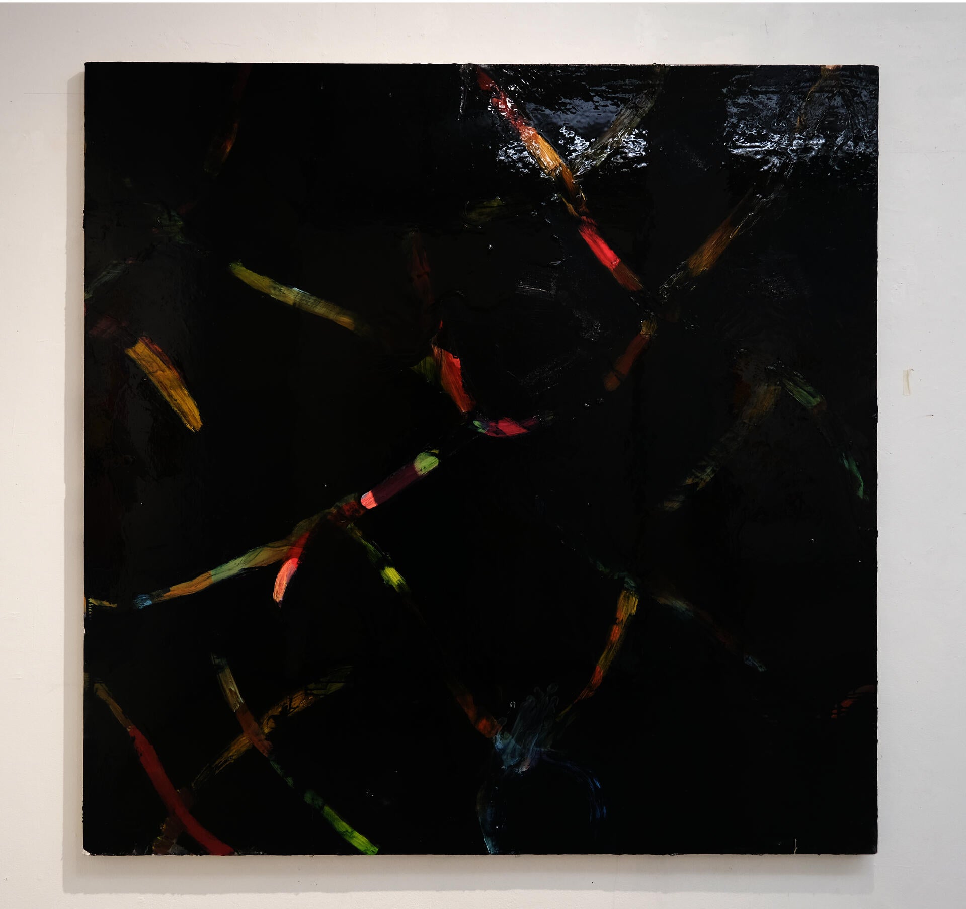 A shiny black square-ish canvas with strokes of pink, blue, ochre, and green.