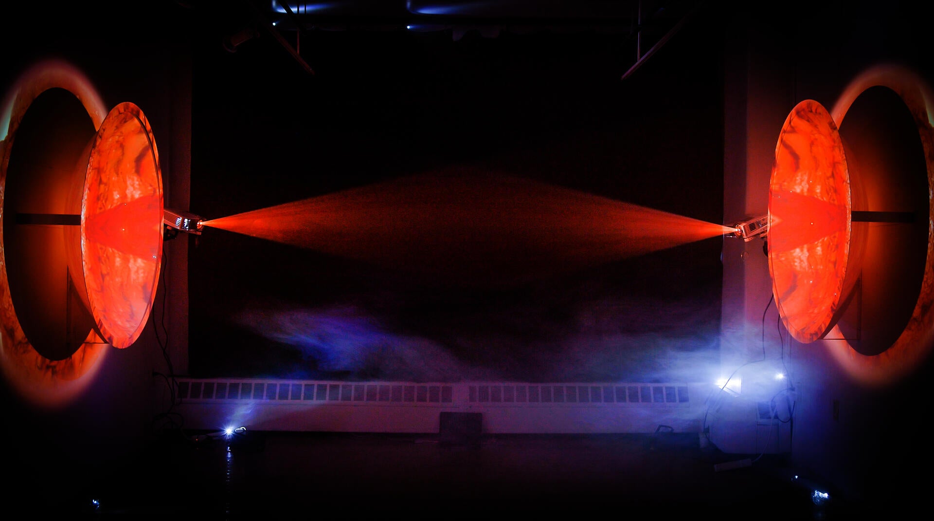 Photogram animations cross-projected on two large acrylic domes with a beam of fog and light between them.