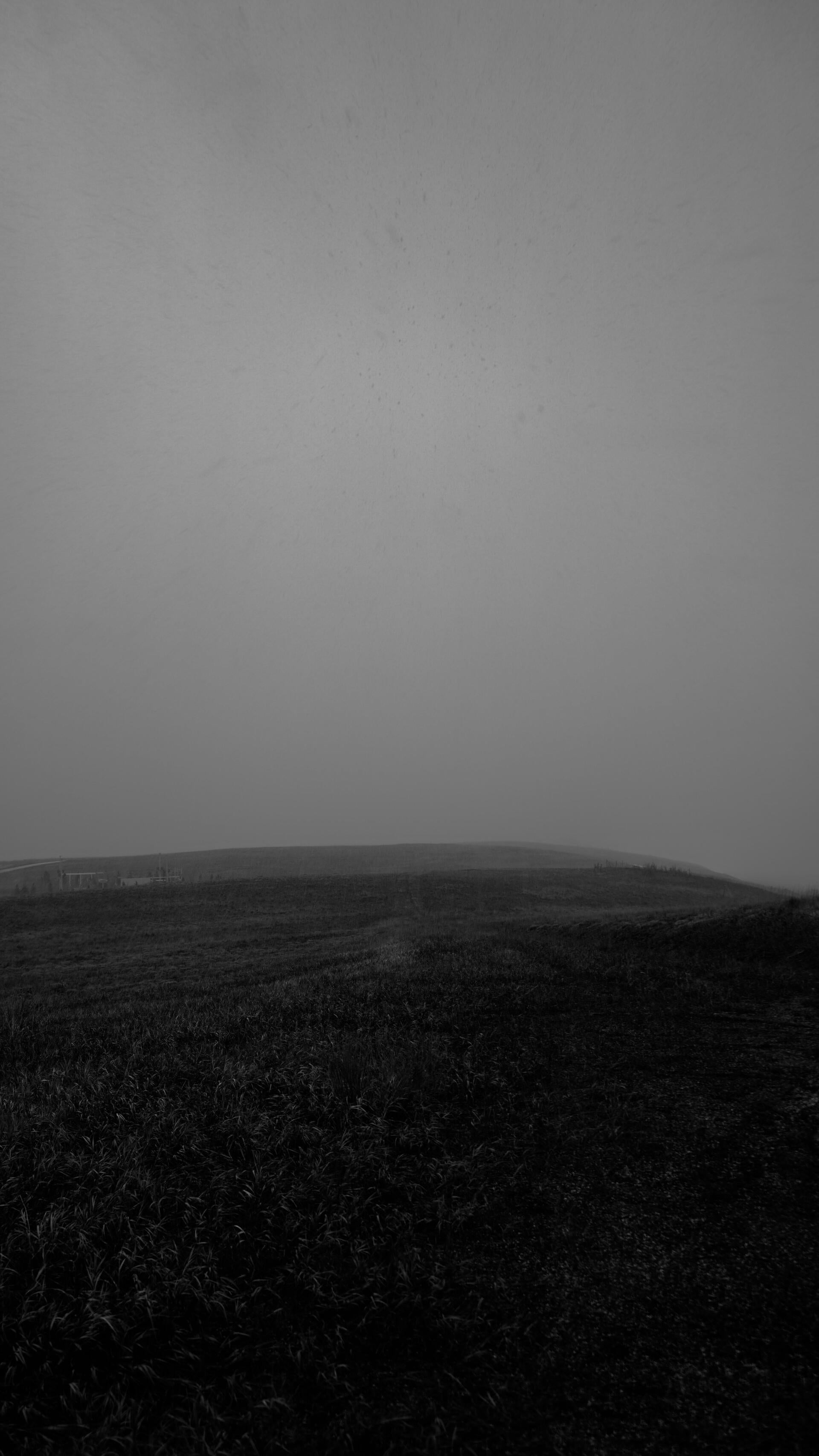 Black and white digital photograph of a rolling field at the start of a hail storm.