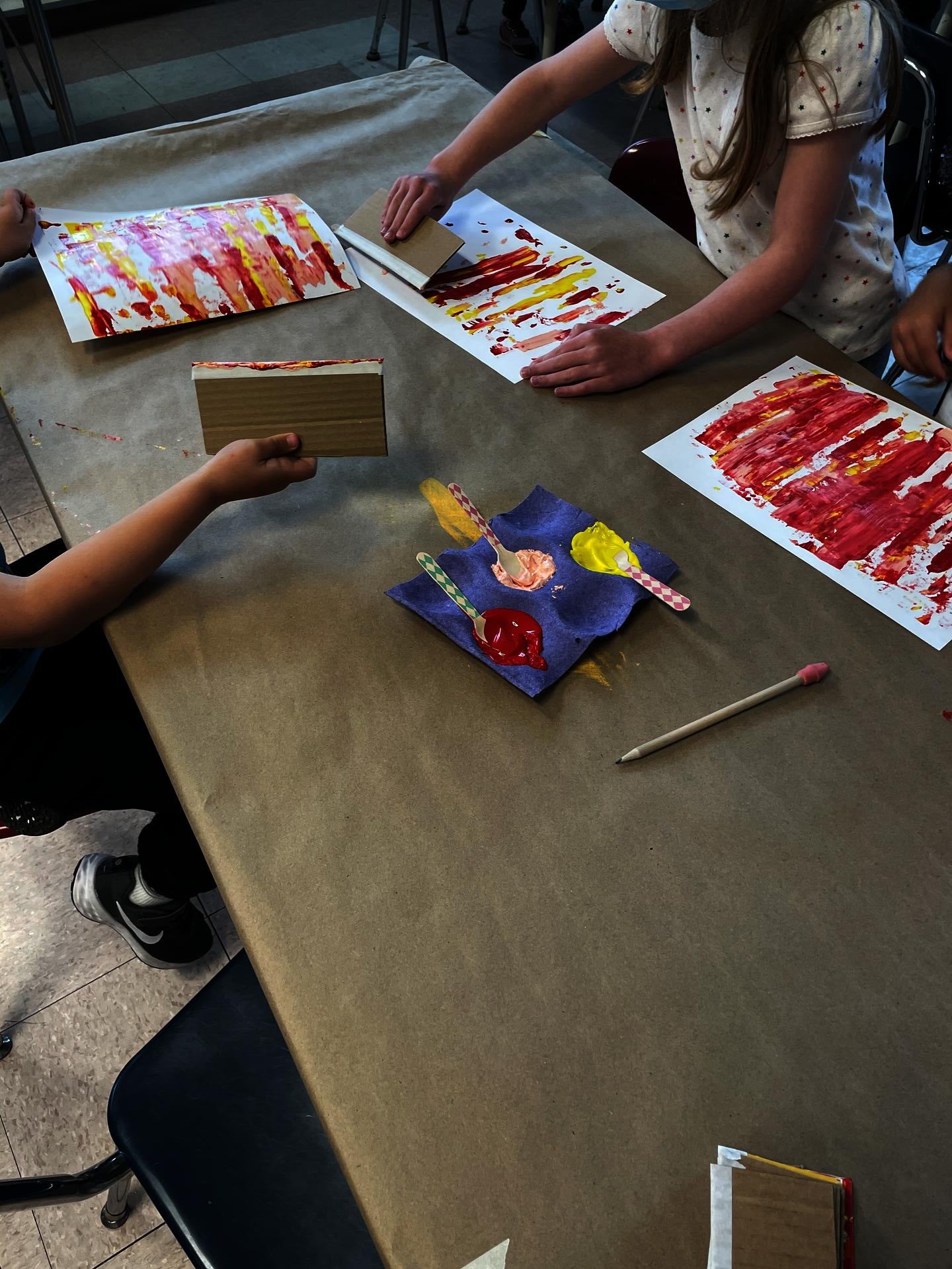 Students applying paint using wooden spoons and spreading it out to created the squeegee effect.  