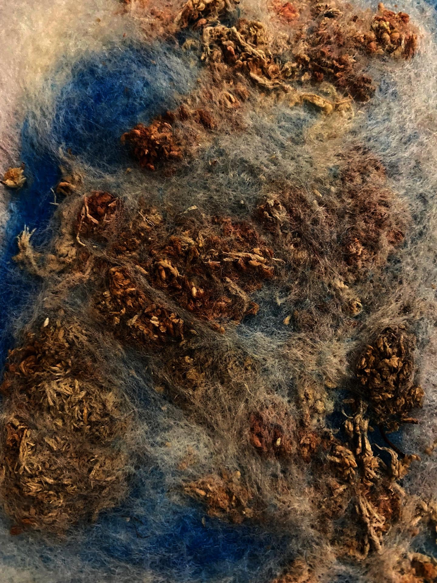 blue and white wool fibers felted into dried plant material